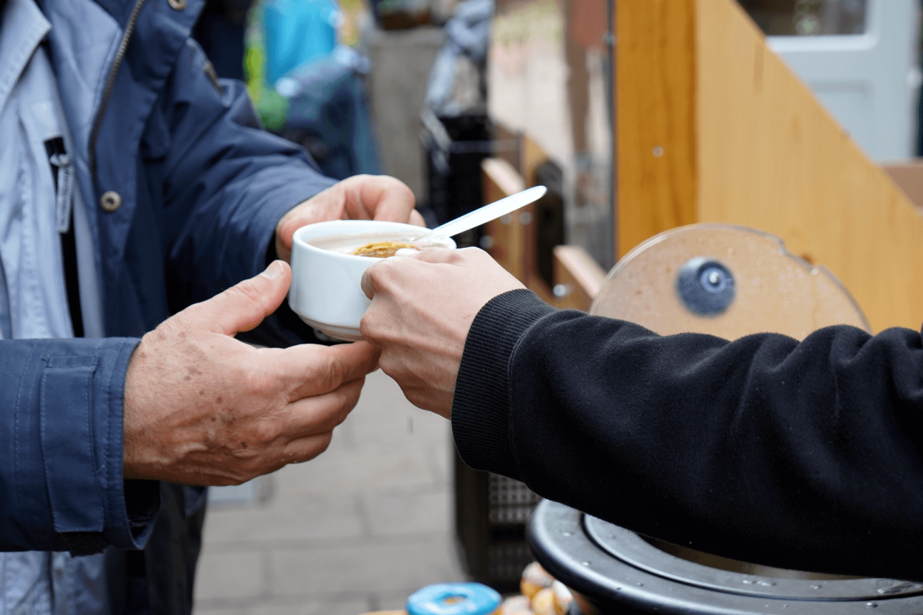 Jemand bekommt eine Tasse warme Suppe in die Hand