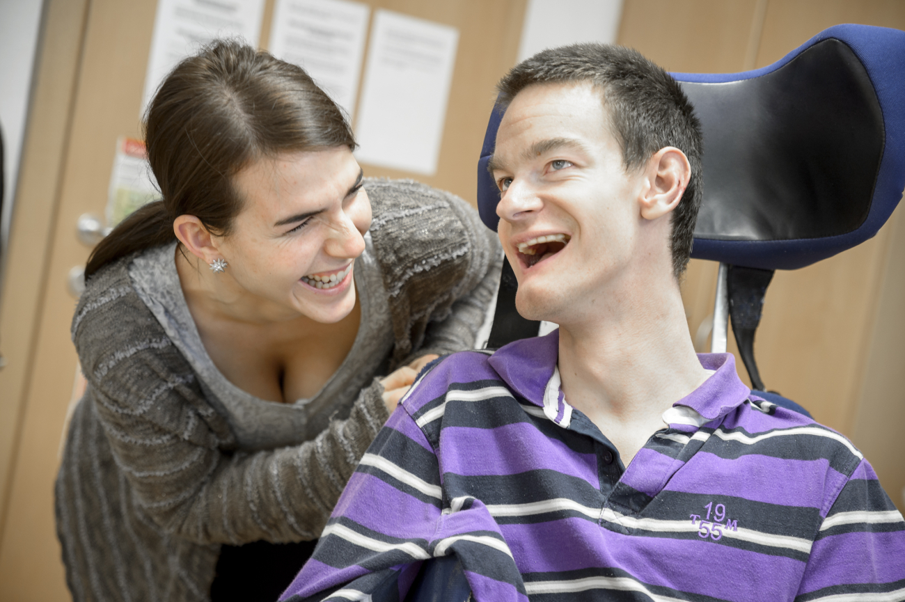 Eine junge Frau und ein Junger Mann im Rollstuhl lachen