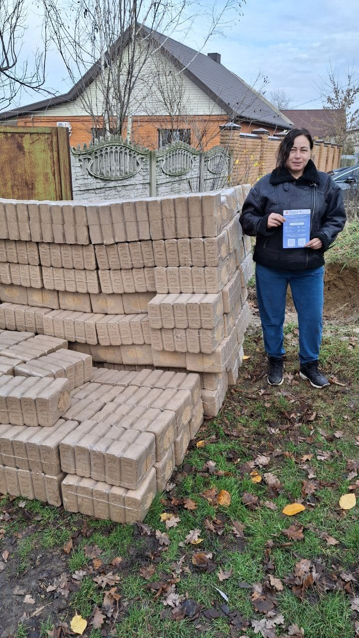 Frau steht neben einem Berg Briketts