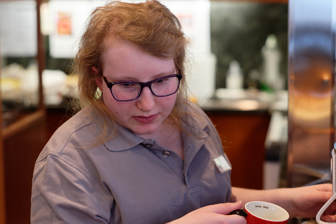 Eine Mitarbeiterin im KOWALSKI café & bistro Kitzbühel bereitet Kaffee zu.