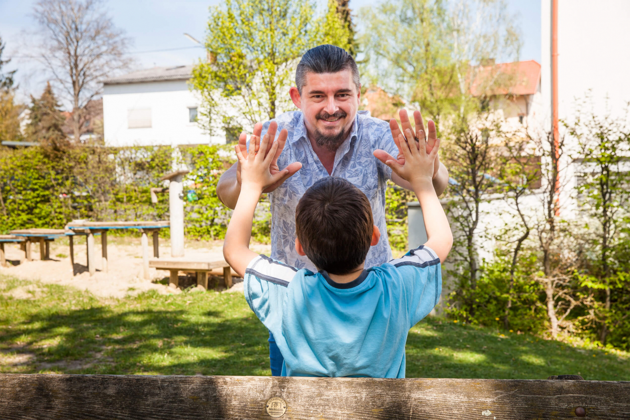 Ein Kind und ein Mitarbeiter der Diakonie klatschen einander in die Hände.