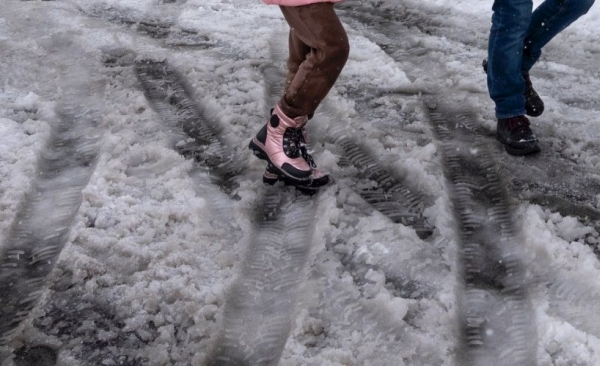Menschen gehen im Schnee. Man sieht nur die Beine.