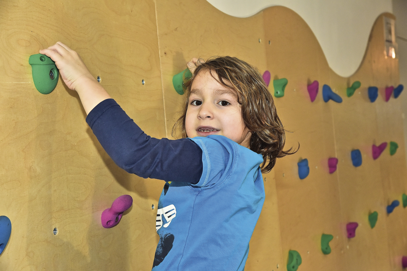 Ein 5-jähriger Junge beim Klettern im Kindergarten für dich und mich.