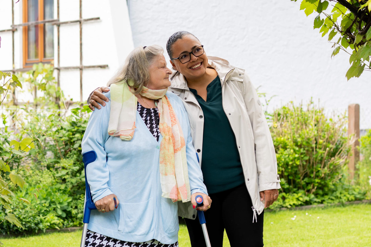 Eine junge Frau und eine alte Frau spazieren in einem Garten.