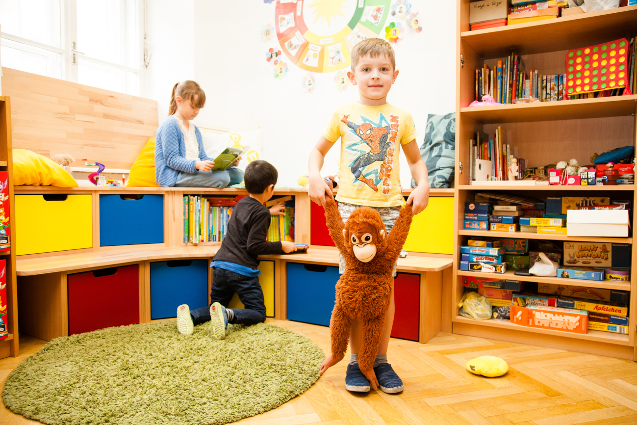 Bub mit Stofftier steht in der Leseecke