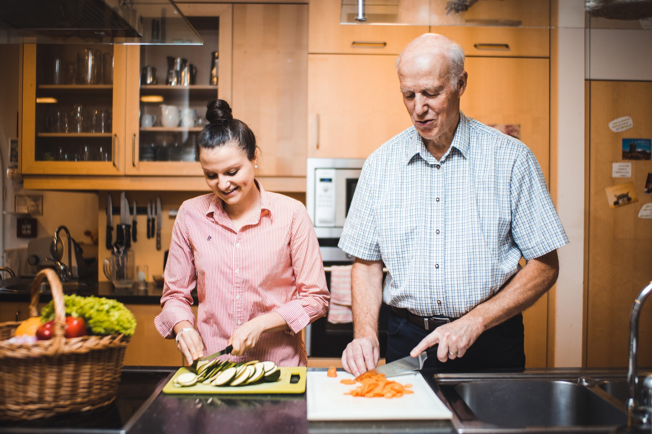 Eine junge Frau und ein älterer Mann kochen gemeinsam.