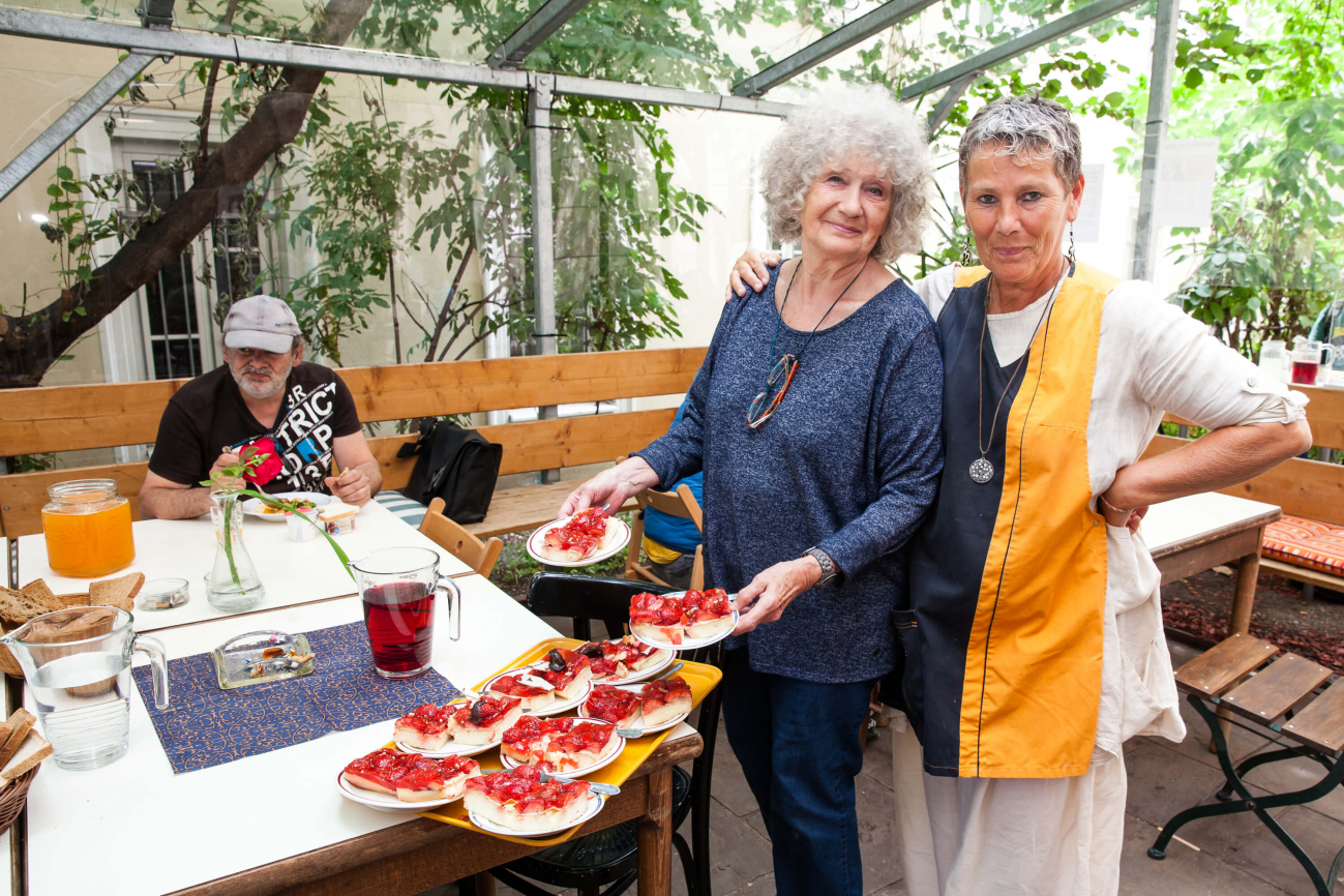 Zwei Frauen servieren Kuchen im Gastgarten des Häferl der Diakonie.