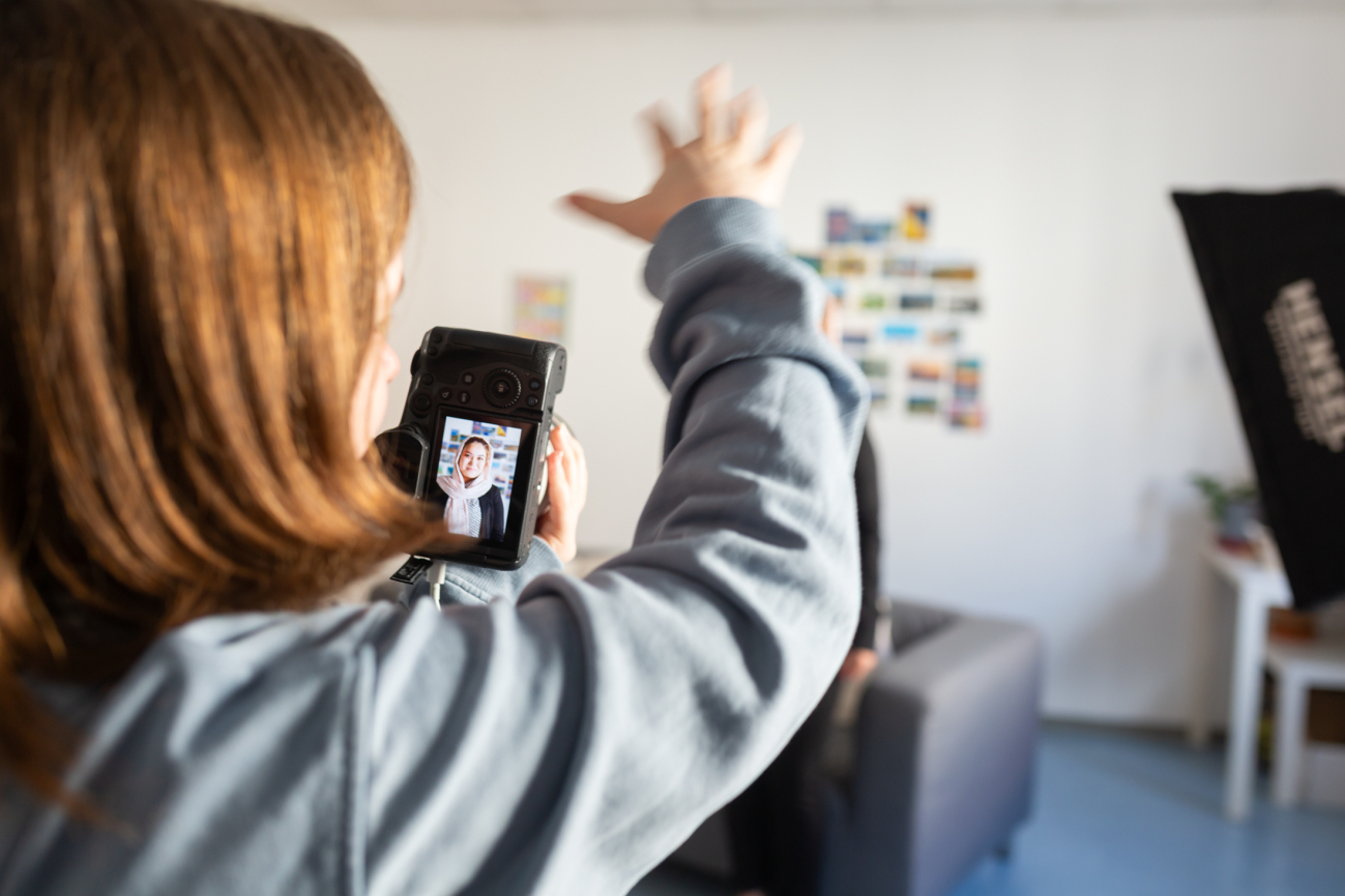 Schüler:innen der Höheren Graphischen Bundeslehr- und Versuchsanstalt beim Fotografieren einer Klientin von 'Aufschwung'.
