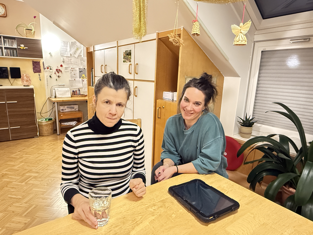Zwei Frauen sitzen an einem Tisch, vor ihnen ein Tablet