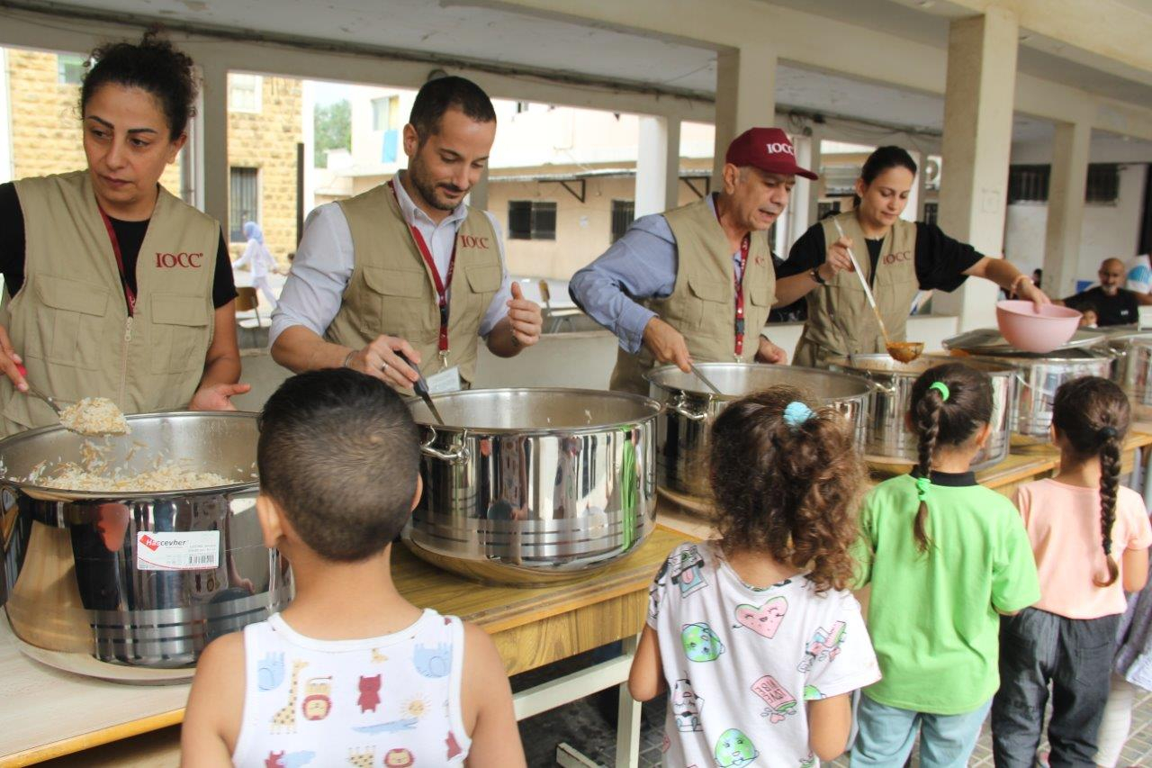 Aus großen Töpfen wird Essen an Kinder angegeben.