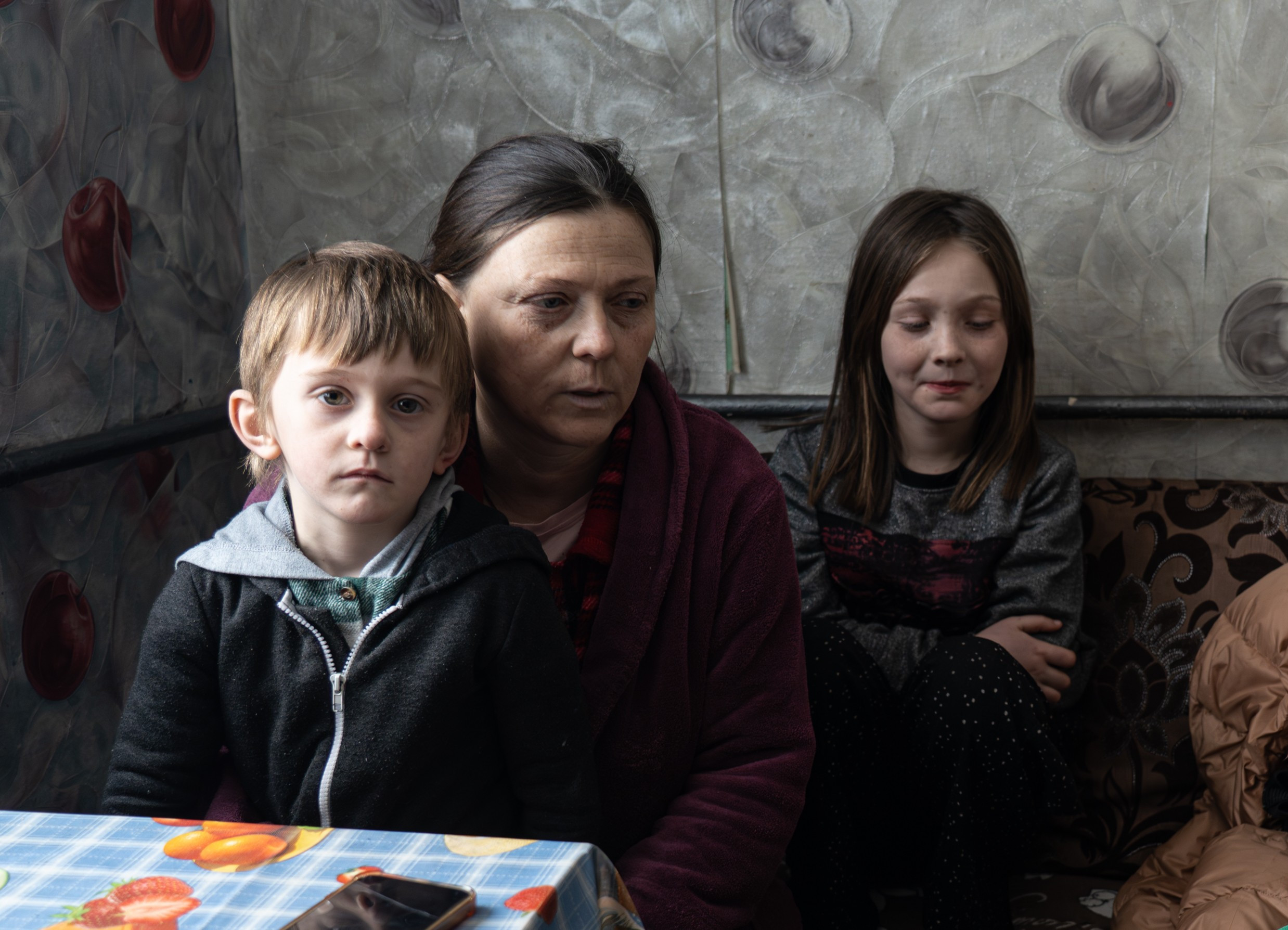 Eine Frau sitzt mit zwei Kindern auf einem Sofa.