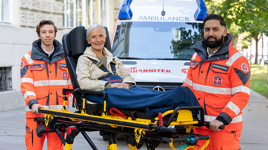 Zwei Mitarbeiter der Johanniter und eine Patientin auf einer Rettungstrage