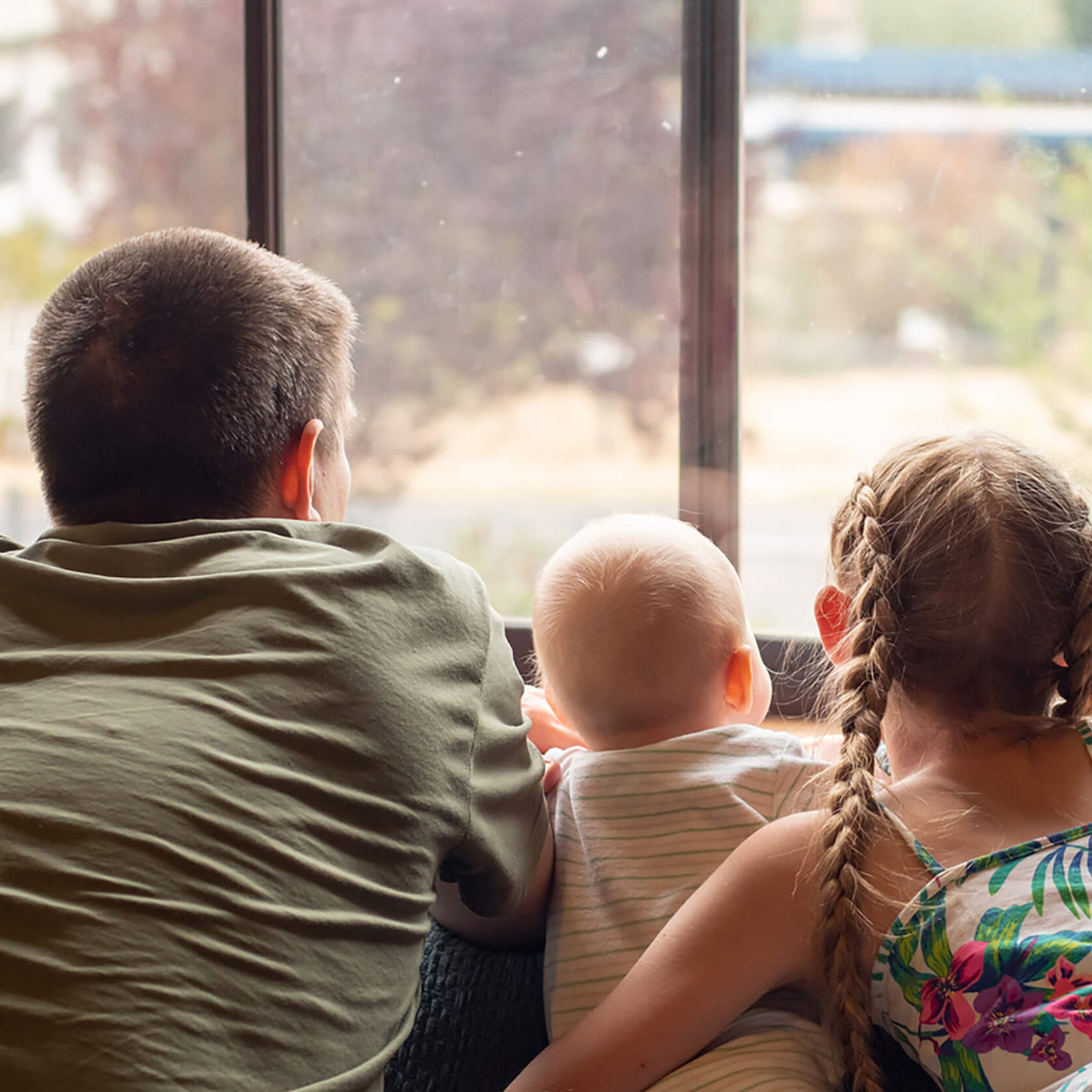 Drei Kinder schauen aus einem Fenster.