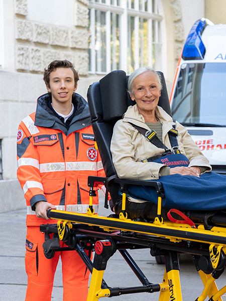 Zwei Mitarbeiter der Johanniter und eine Patientin auf einer Rettungstrage