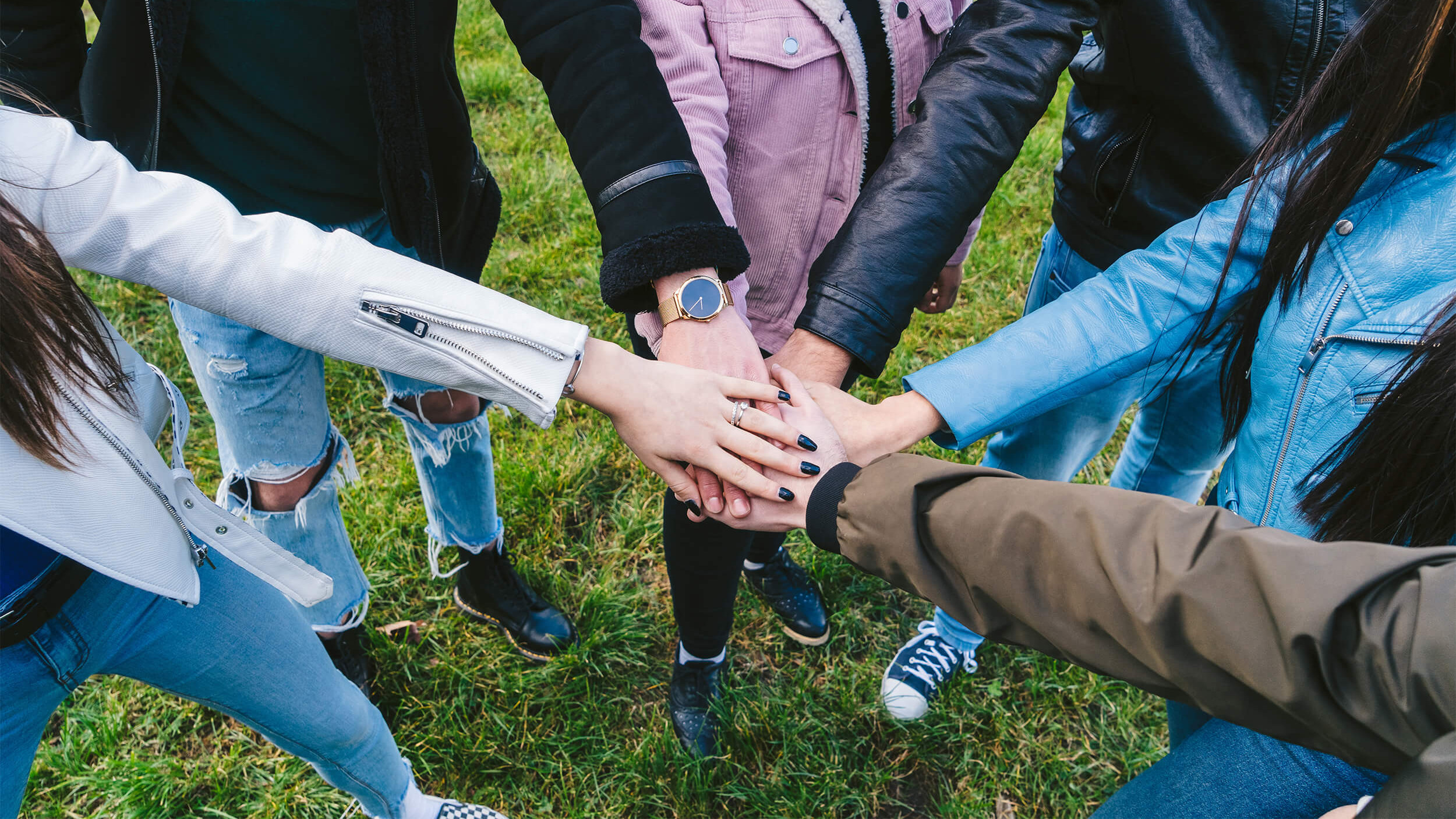 Junge Menschen halten Hände übereinander