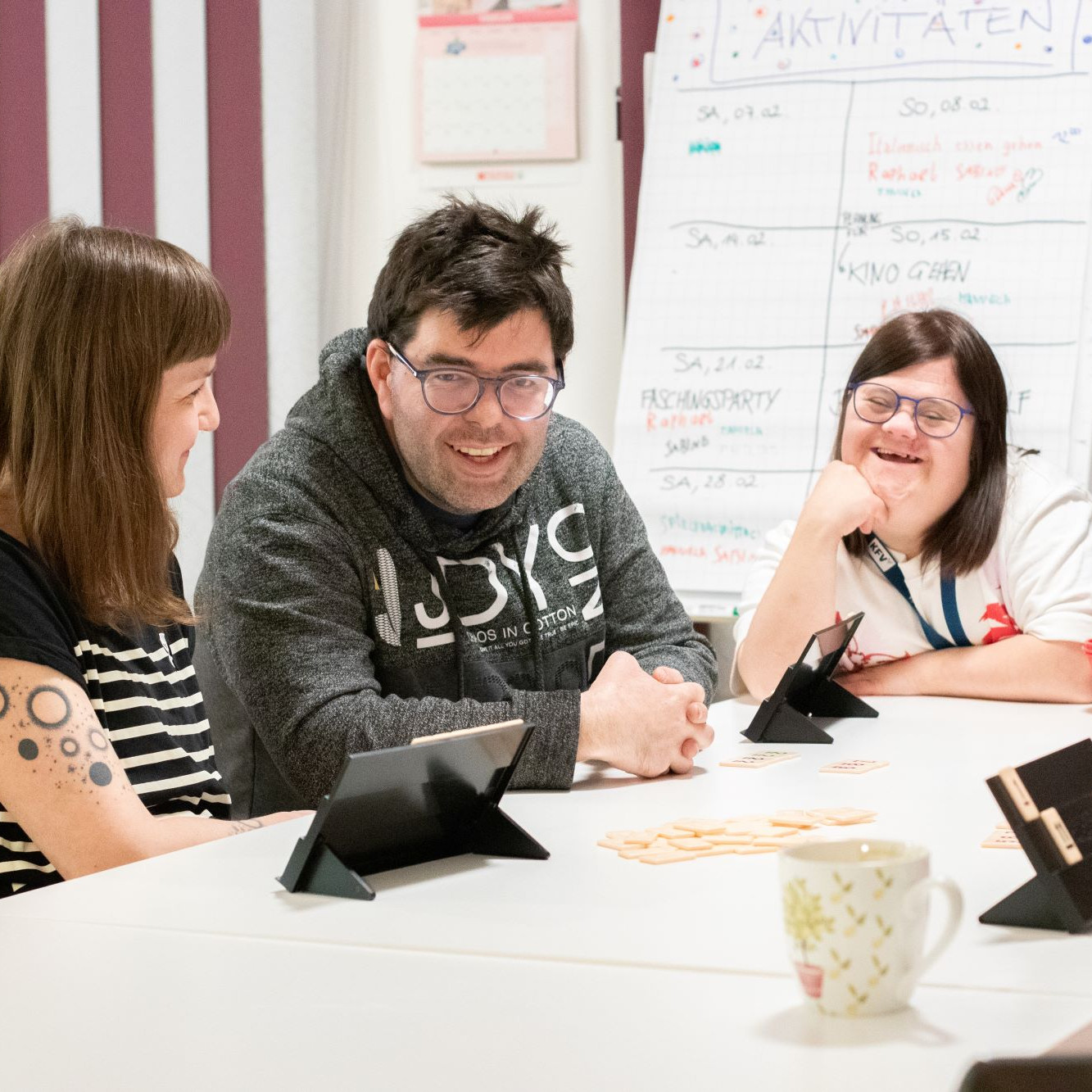 Drei Personen sitzen an einem Tisch - zwei Damen und in der Mitte ein Mann