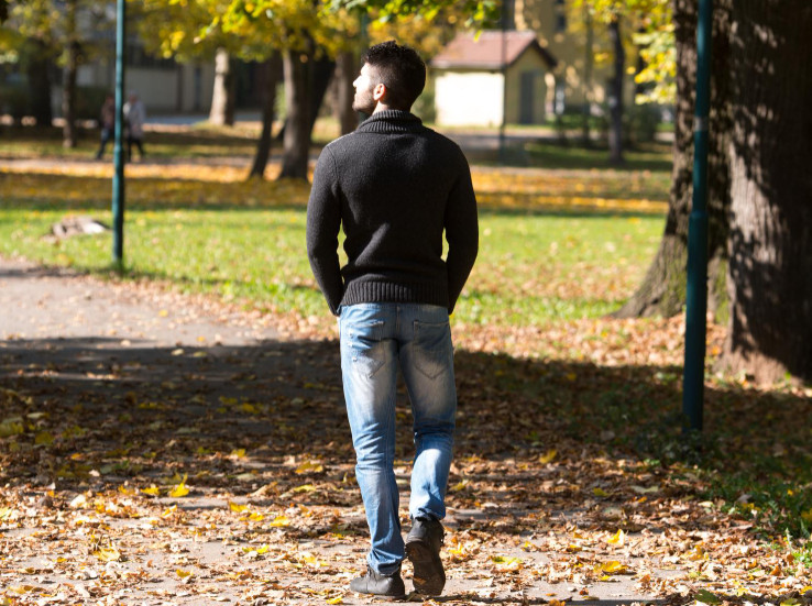 Junger Mann Rückansicht beim Spaziergang im Park_Symbolfoto