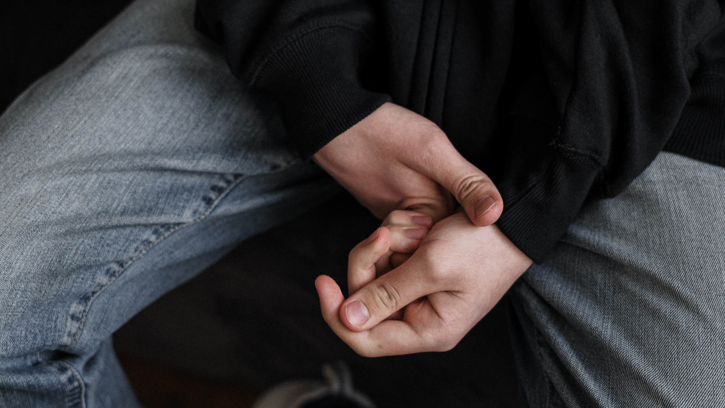 Jugendlicher hält sich angespannt die Hände.