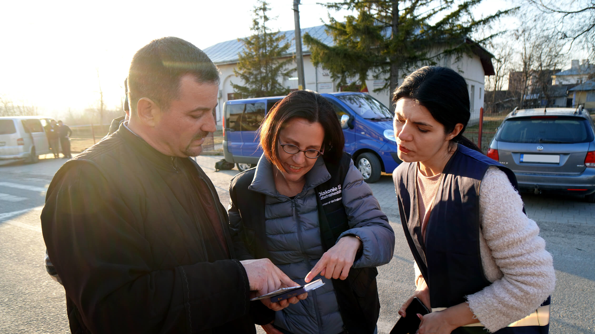 Rumänischer Priester zeigt Diakonie-Direktorin Moser und Dana, einer AIDRom-Mitarbeiterin, ein selbst gemachtes Wörterbuch