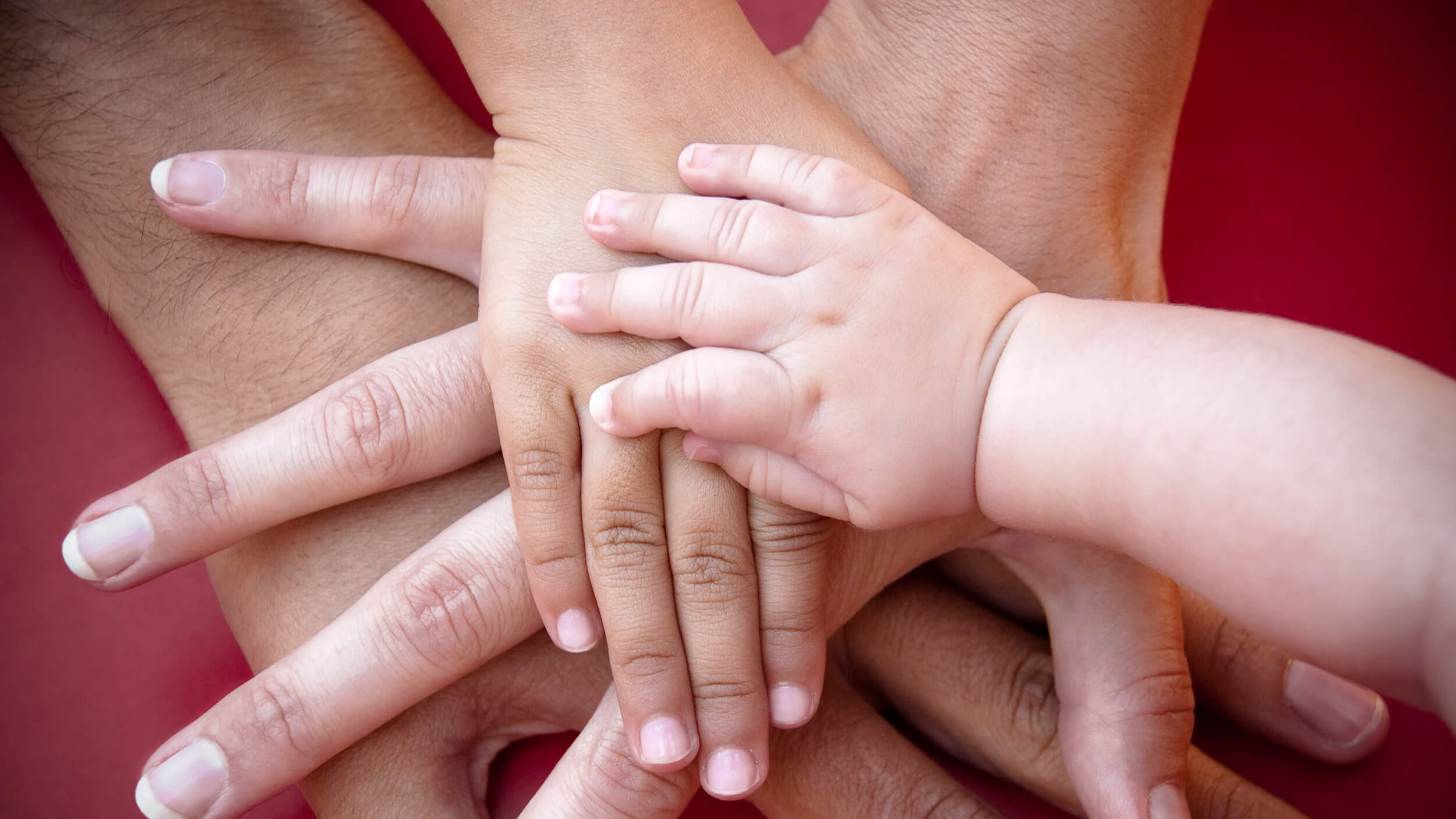 Hände von Erwachsenen und einem Baby übereinander