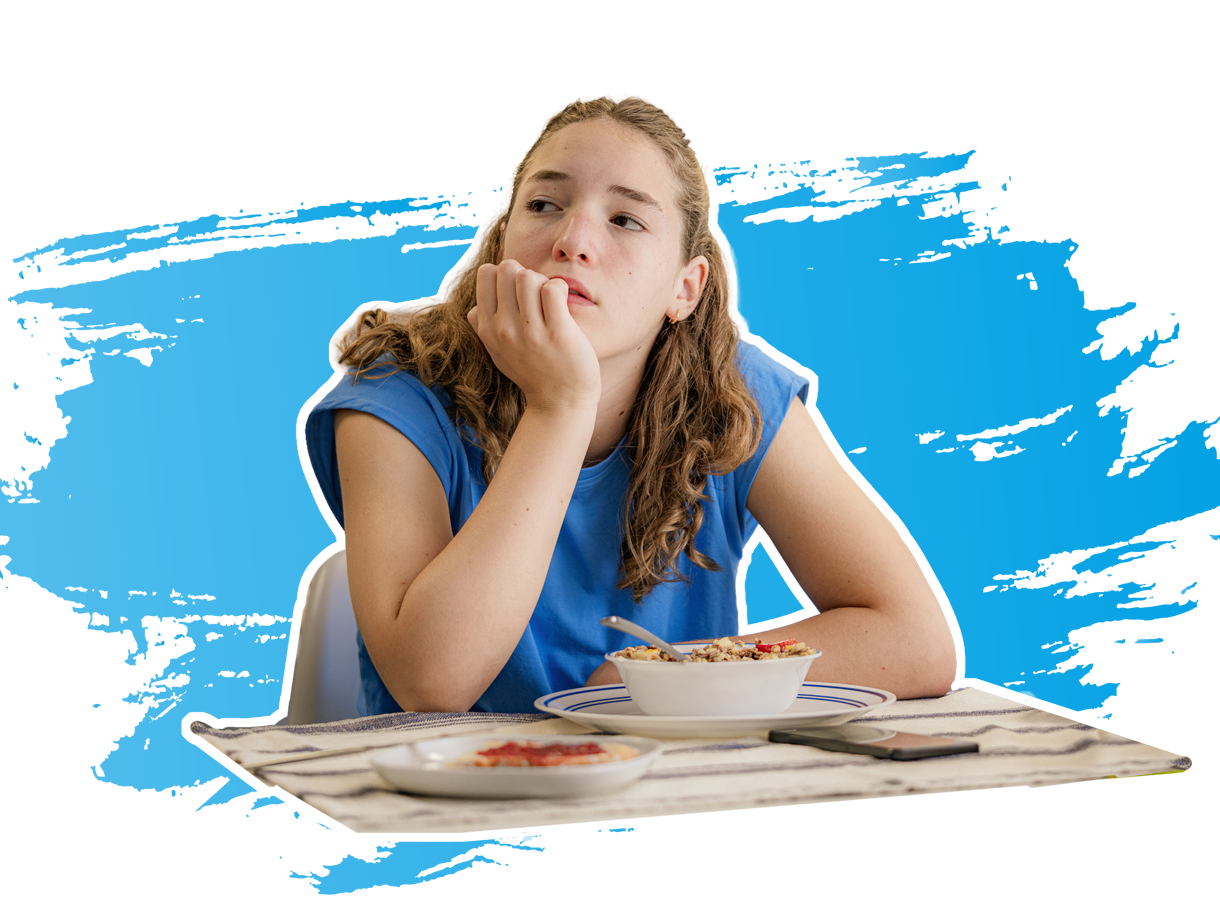 Mädchen sitzt am Tisch und sieht in die Luft.