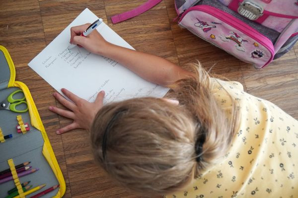 Mädchen beugt sich über Liste und hakt ab, was sie für den Schulstart hat.