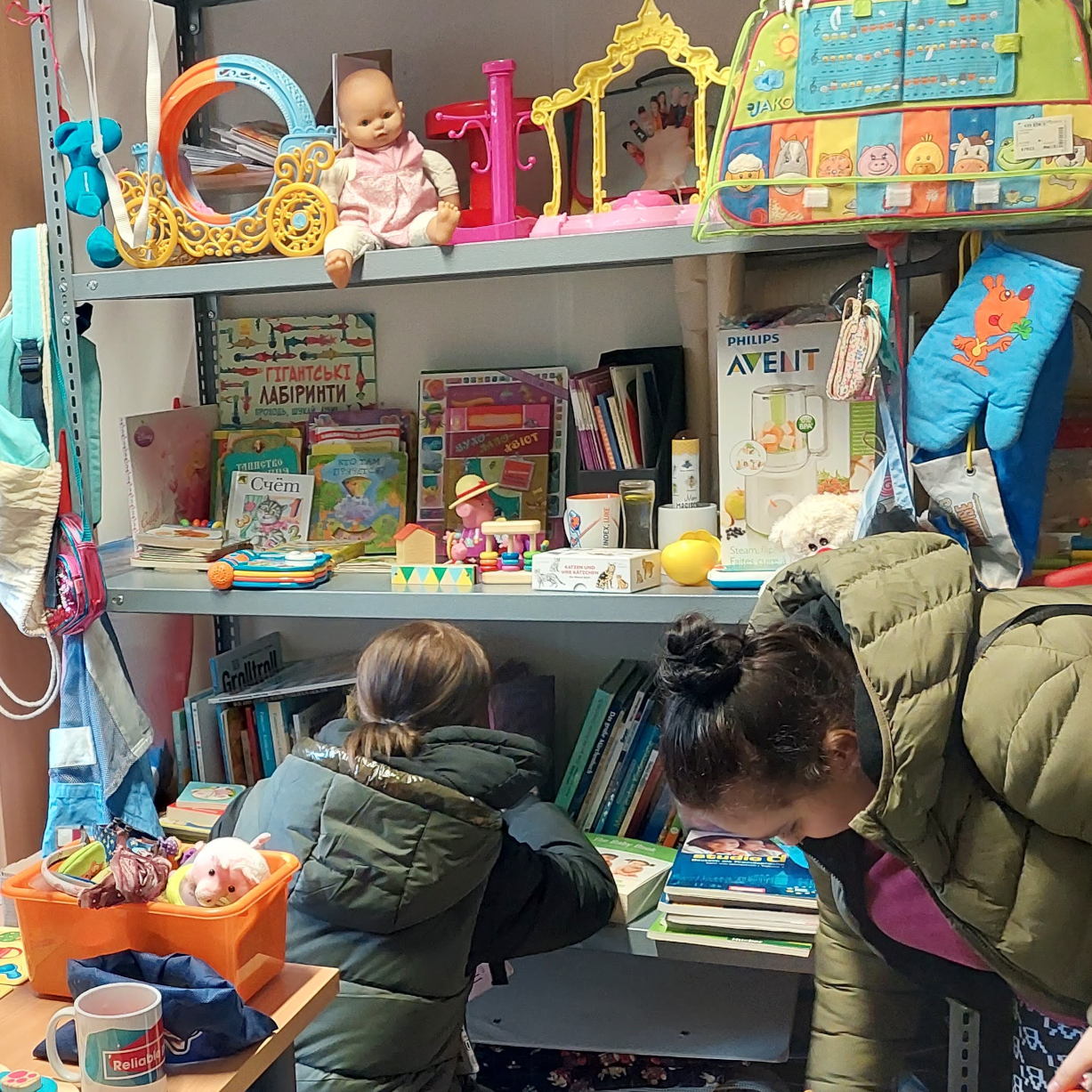 Mütter suchen Bücher und Kinderkleidung für ihre Kleinen aus