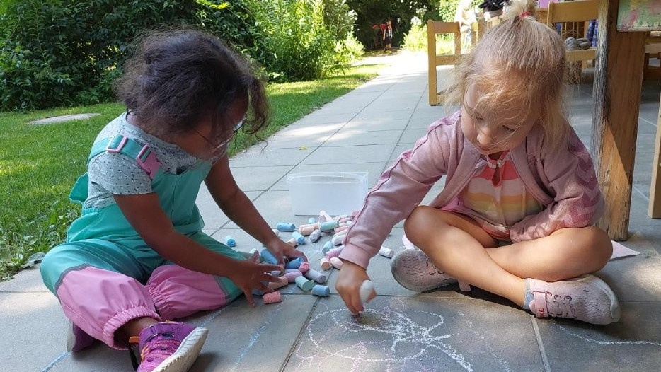 Zwei Mädchen spielen zusammen mit Straßenkreide