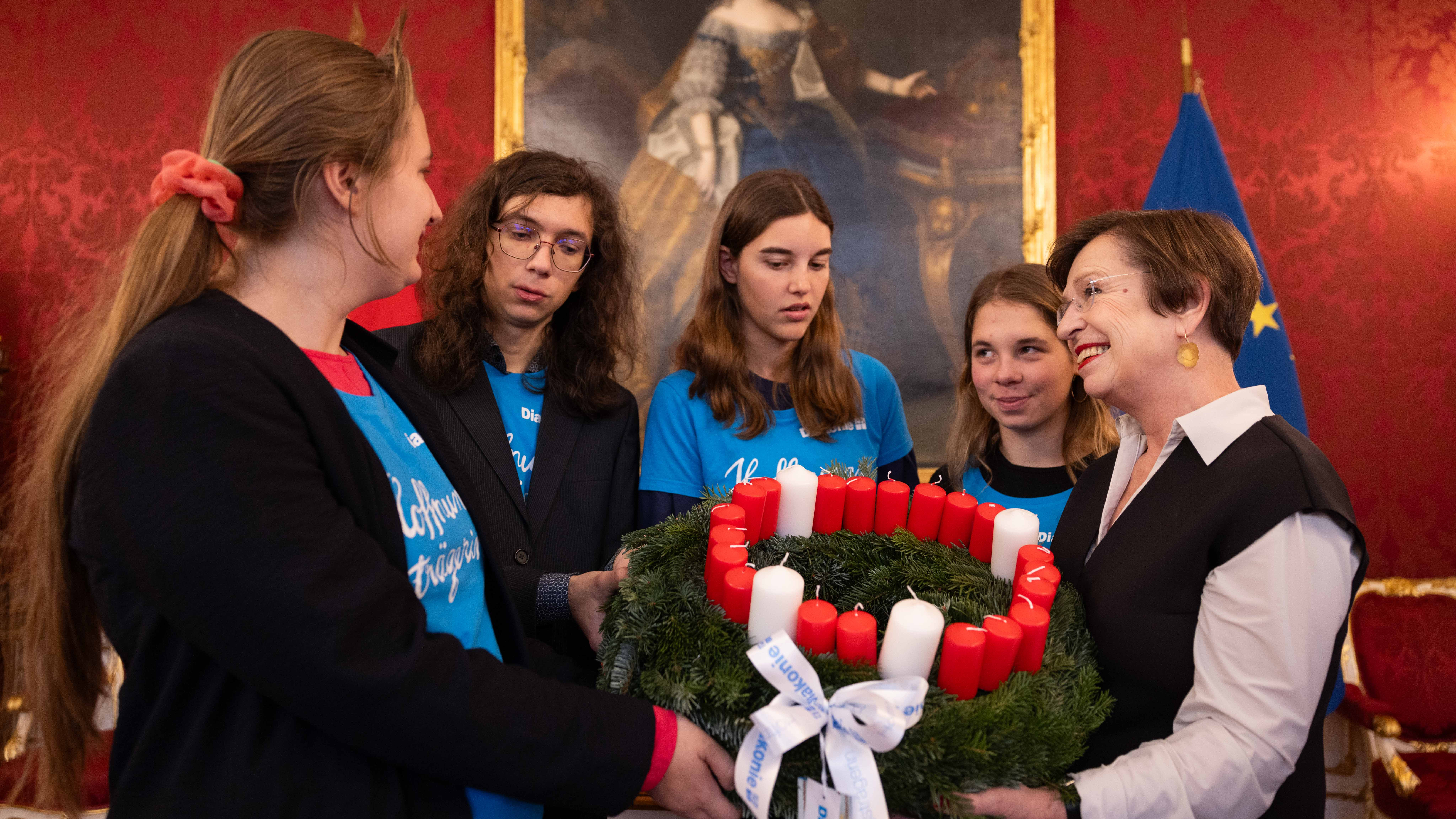 Schülerinnen und Schülern der Diakonie überreichen den Adventkranz.