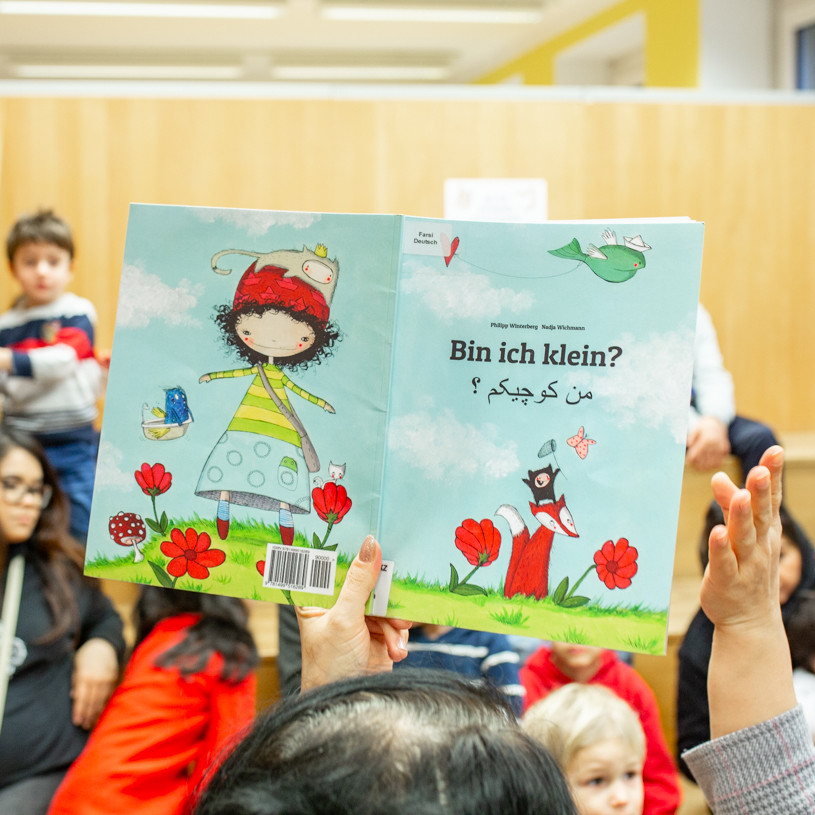 Eltern und Kinder halten Kinderbücher in die Höhe