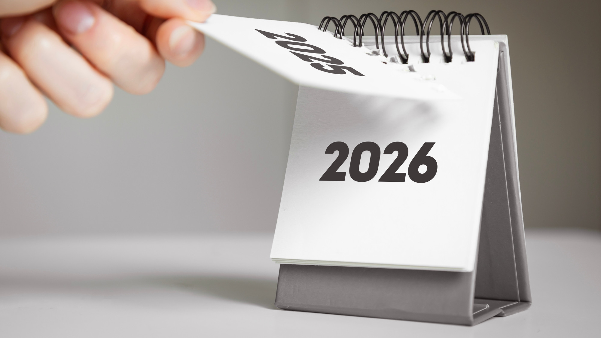 Eine Hand ändert das Kalenderblatt von 2025 auf 2026
