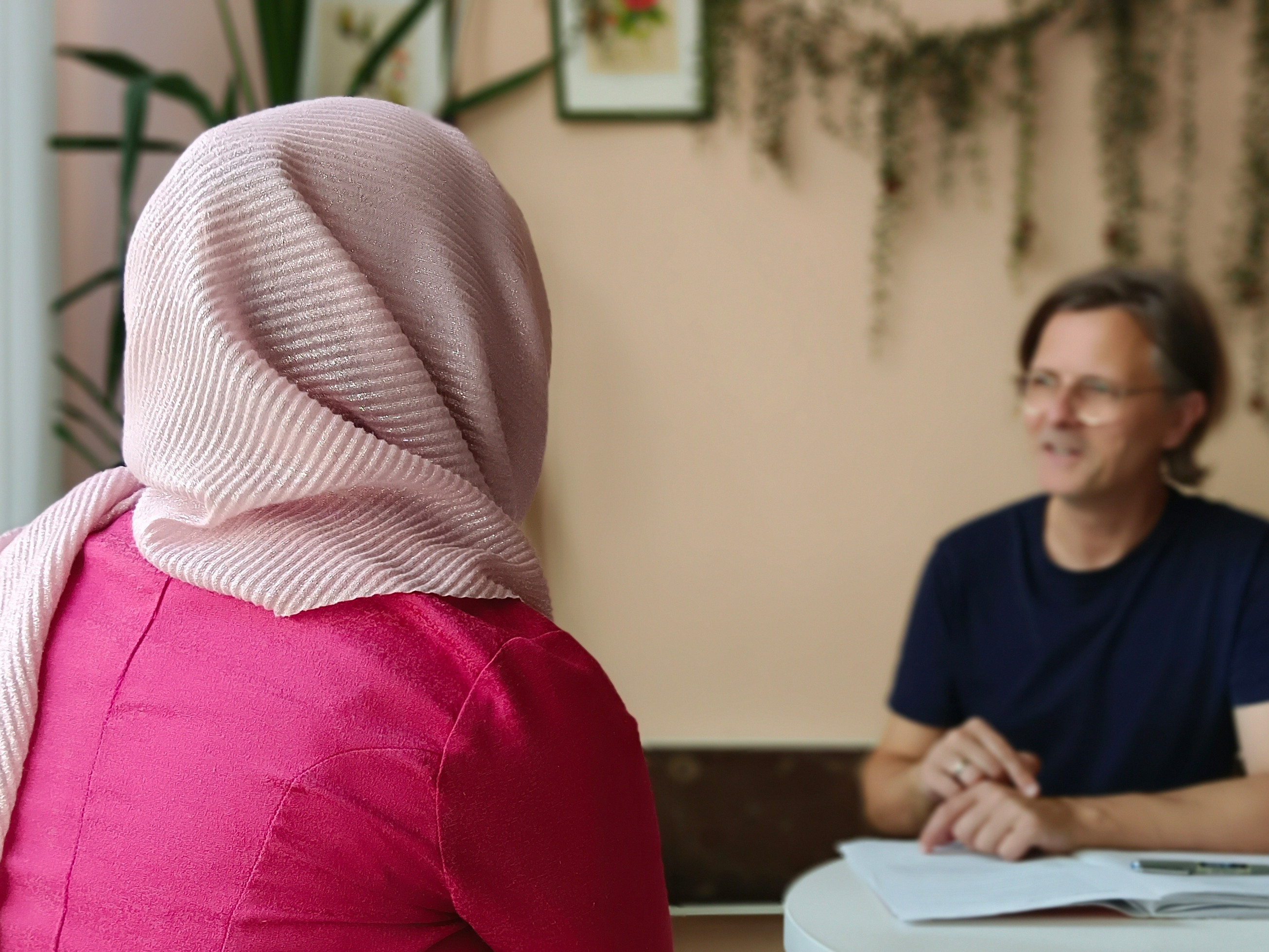 Frau mit Kopftuch von hinten in Interviewsituation