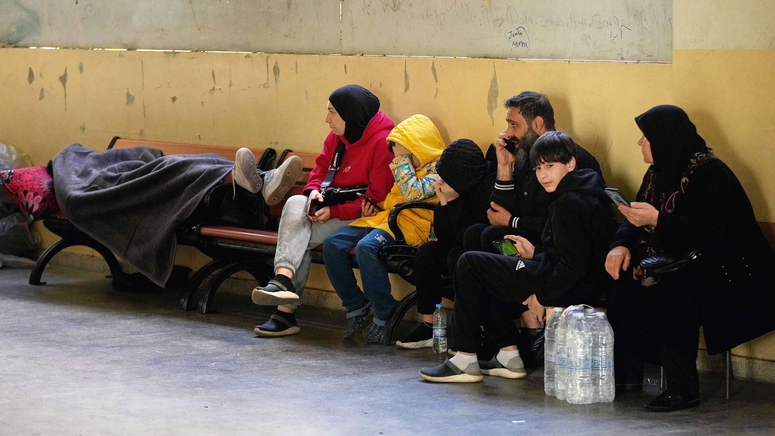 Families displaced by Israeli airstrikes in southern Lebanon and Dahiyeh, Beirut's southern suburbs, sit inside a school used as a shelter in Beirut, Lebanon, Monday, March 9, 2026. (AP Photo/Hassan Ammar)