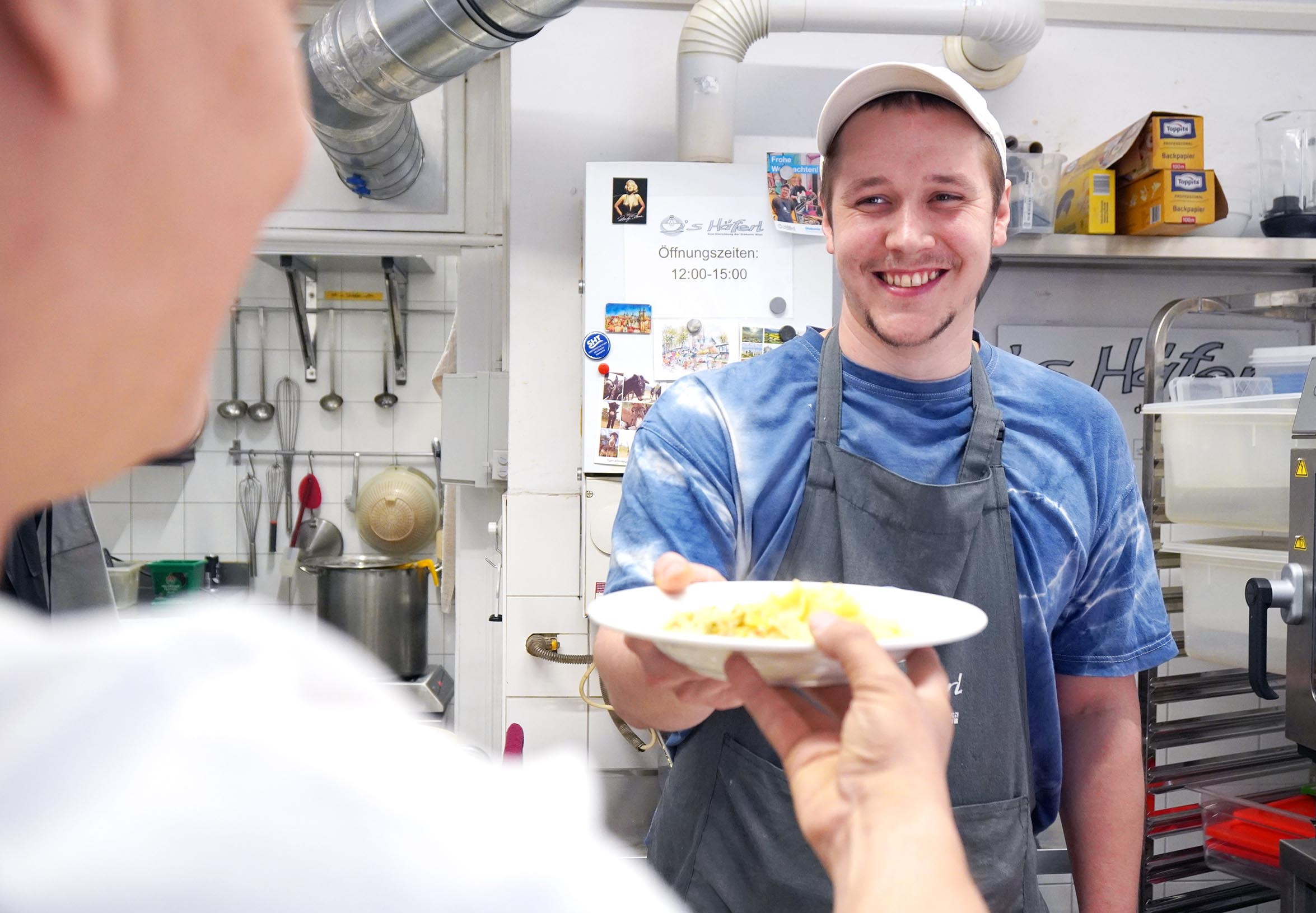 Ein Koch überreicht einem Gast sein Essen