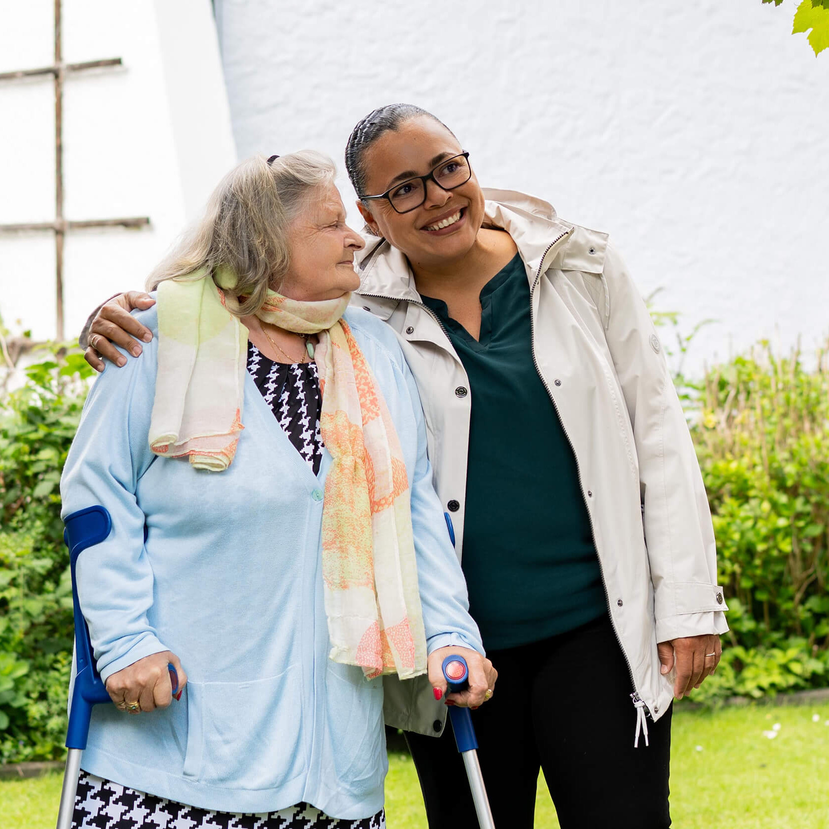 Eine junge Frau und eine alte Frau spazieren in einem Garten.