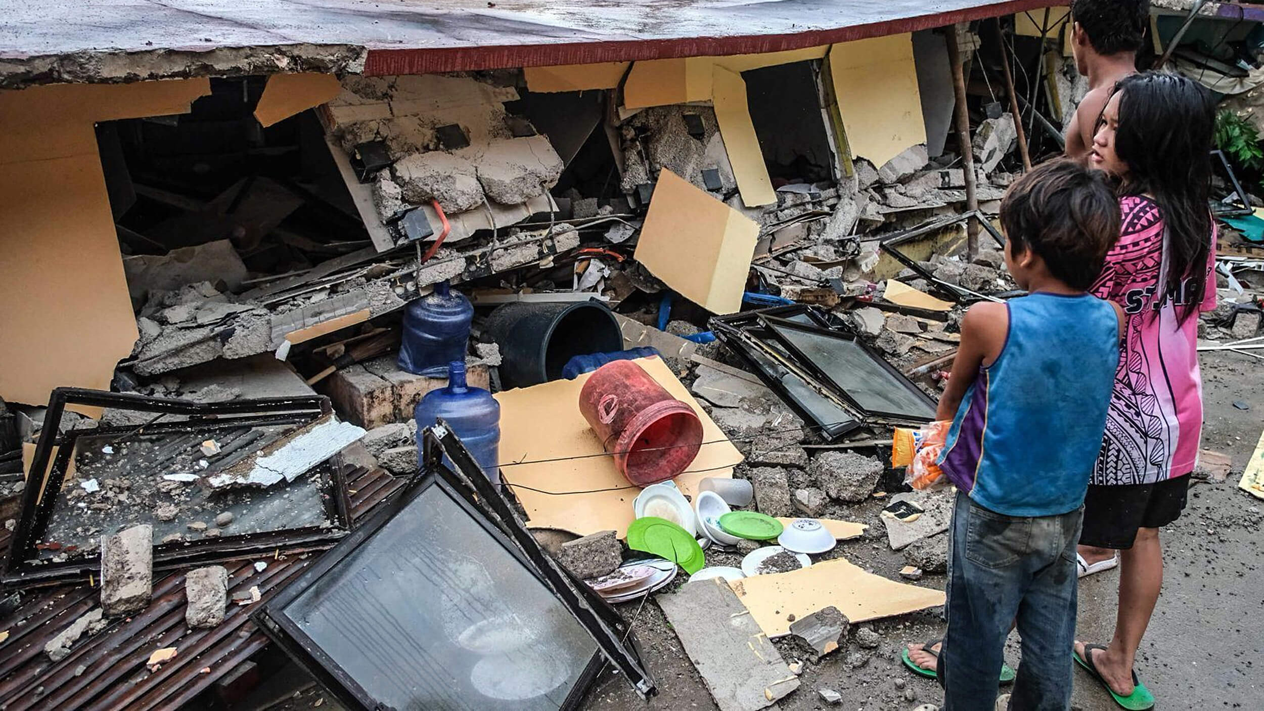 Bewohner:innen vor einem zerstörten Haus auf den Philippinen