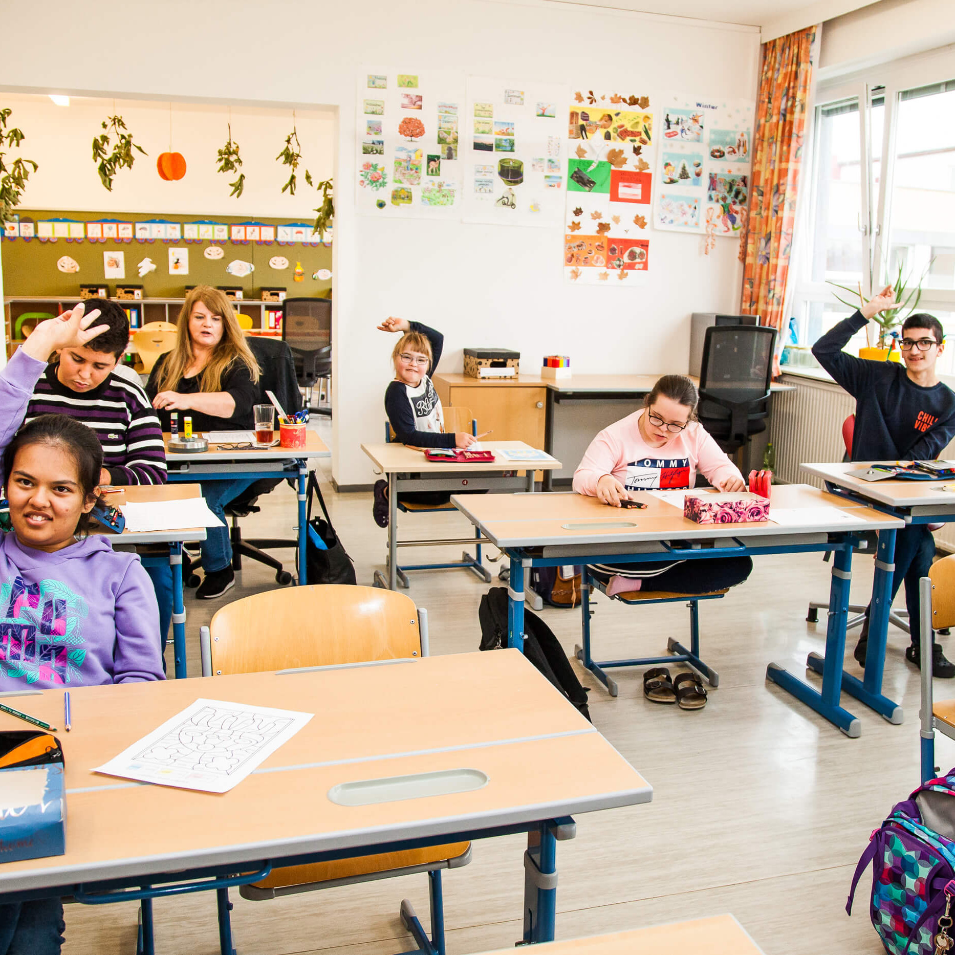 Eine Schulkasse mit Schüler:innen. EInige der Schüler:innen zeigen auf. Eine der Schüler:innen ist Hoffnungsträgerin Lili.