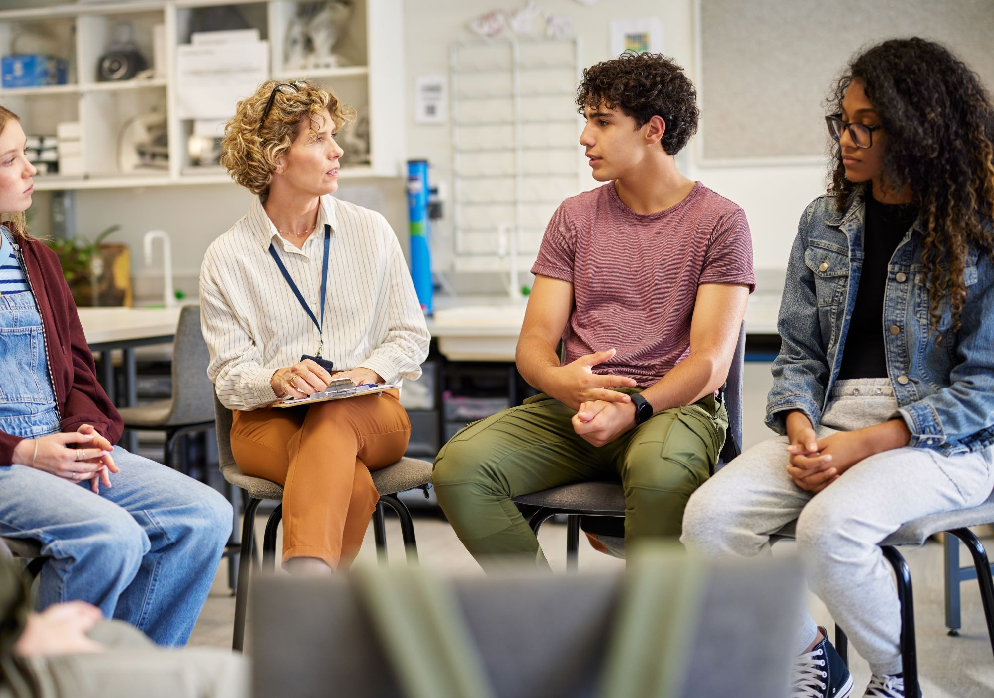 Gruppe von vier Personen, auf Stühlen im Halbkreis sitzend, unterhalten sich