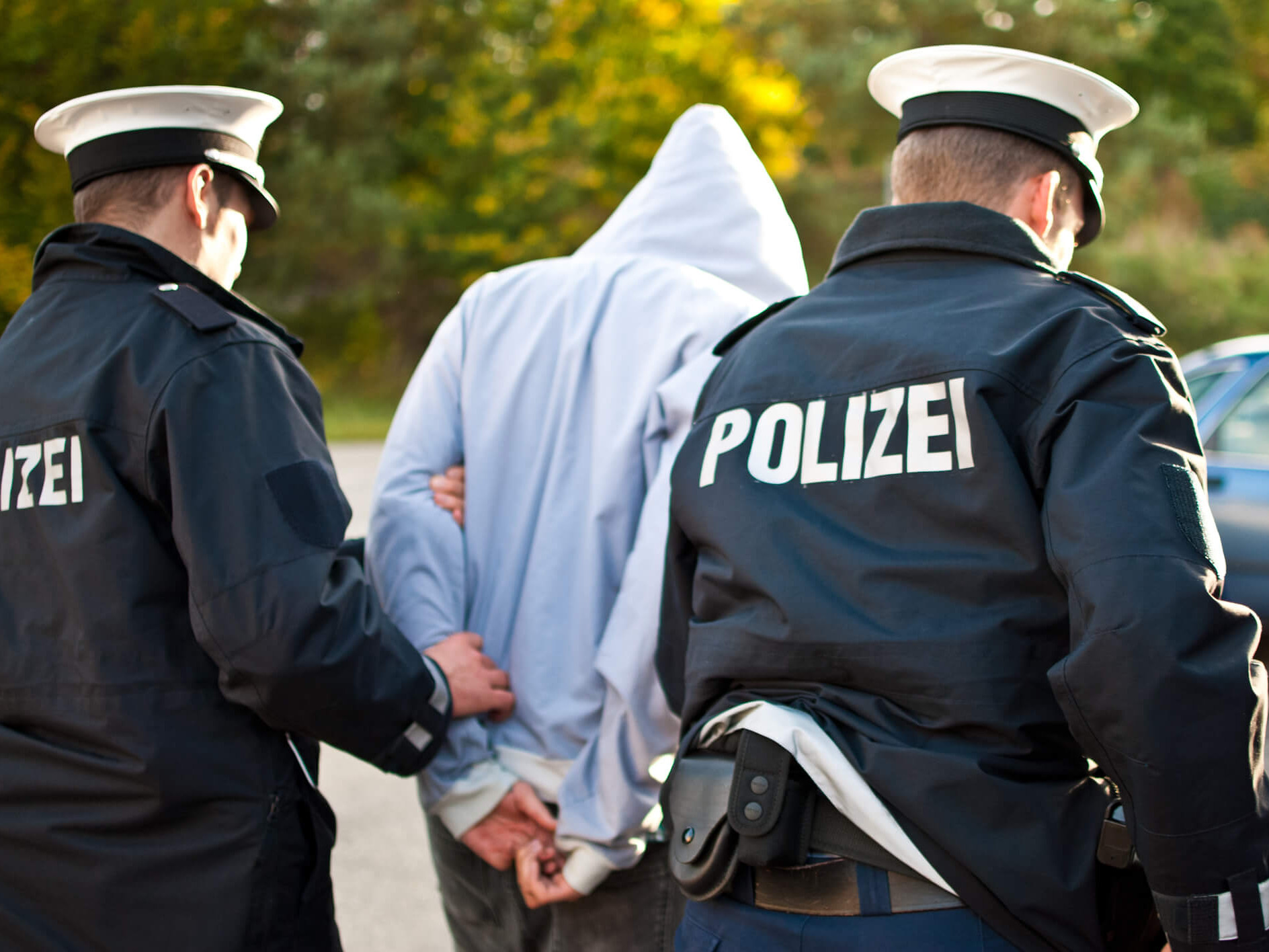 Ein Mann wird von zwei Polizisten abgeführt.