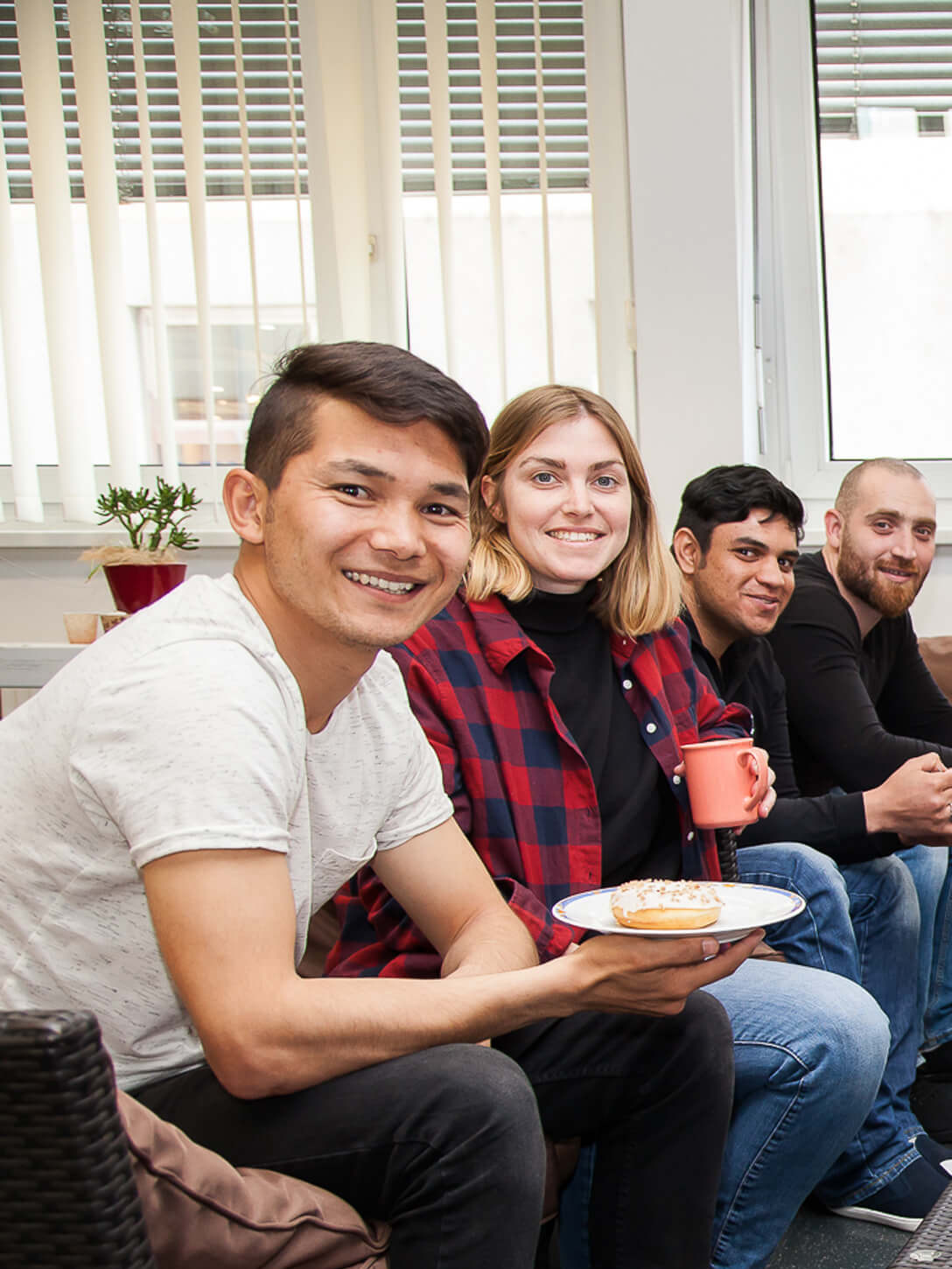Eine gruppe von Menschen sitzt bei Kaffee und Kuchen um einen Tisch.