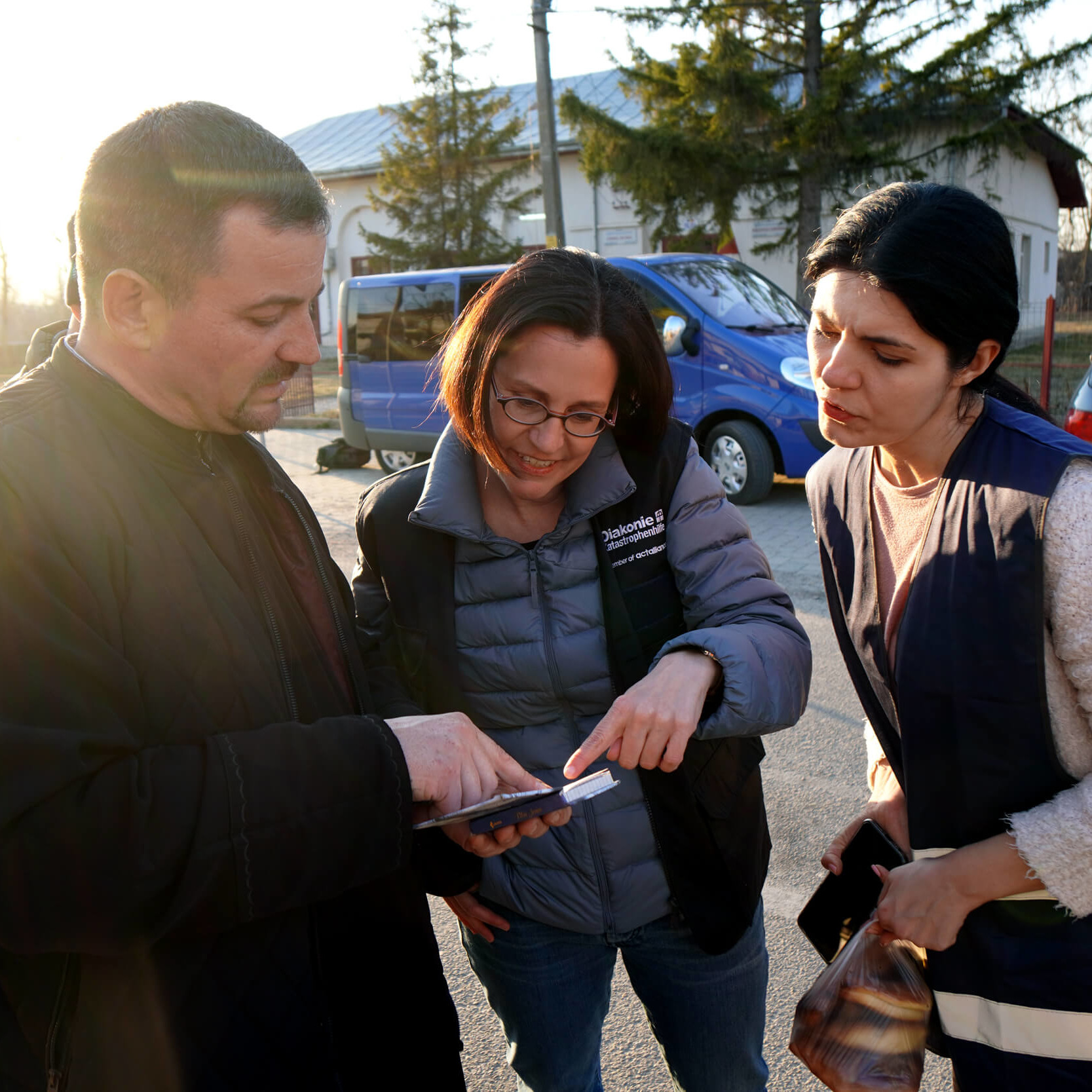 Rumänischer Priester zeigt Diakonie-Direktorin Moser und Dana, einer AIDRom-Mitarbeiterin, ein selbst gemachtes Wörterbuch