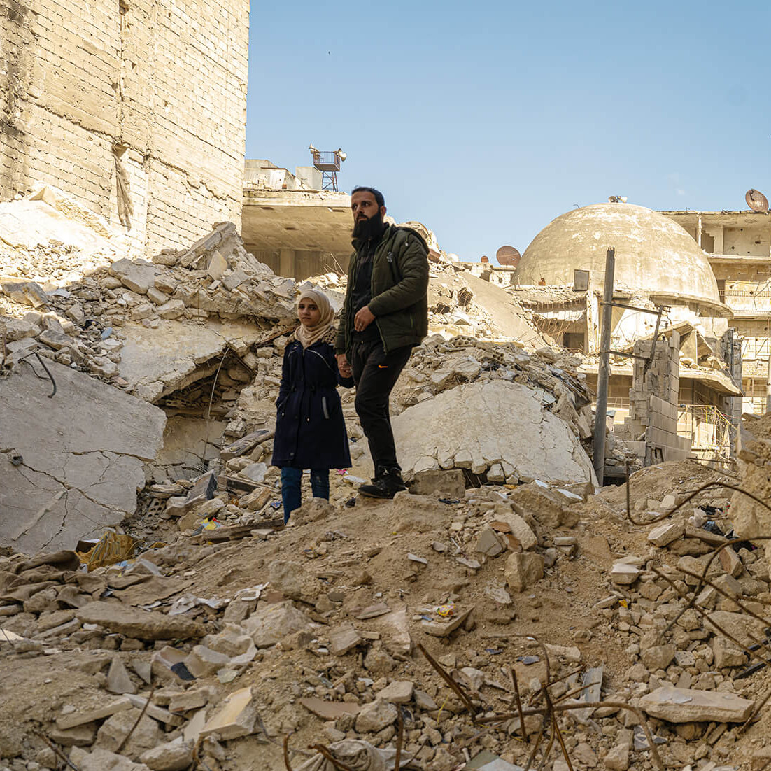 Ein Mädchen und ihr Vater auf Trümmern nach dem Erdbeben in Syrien.