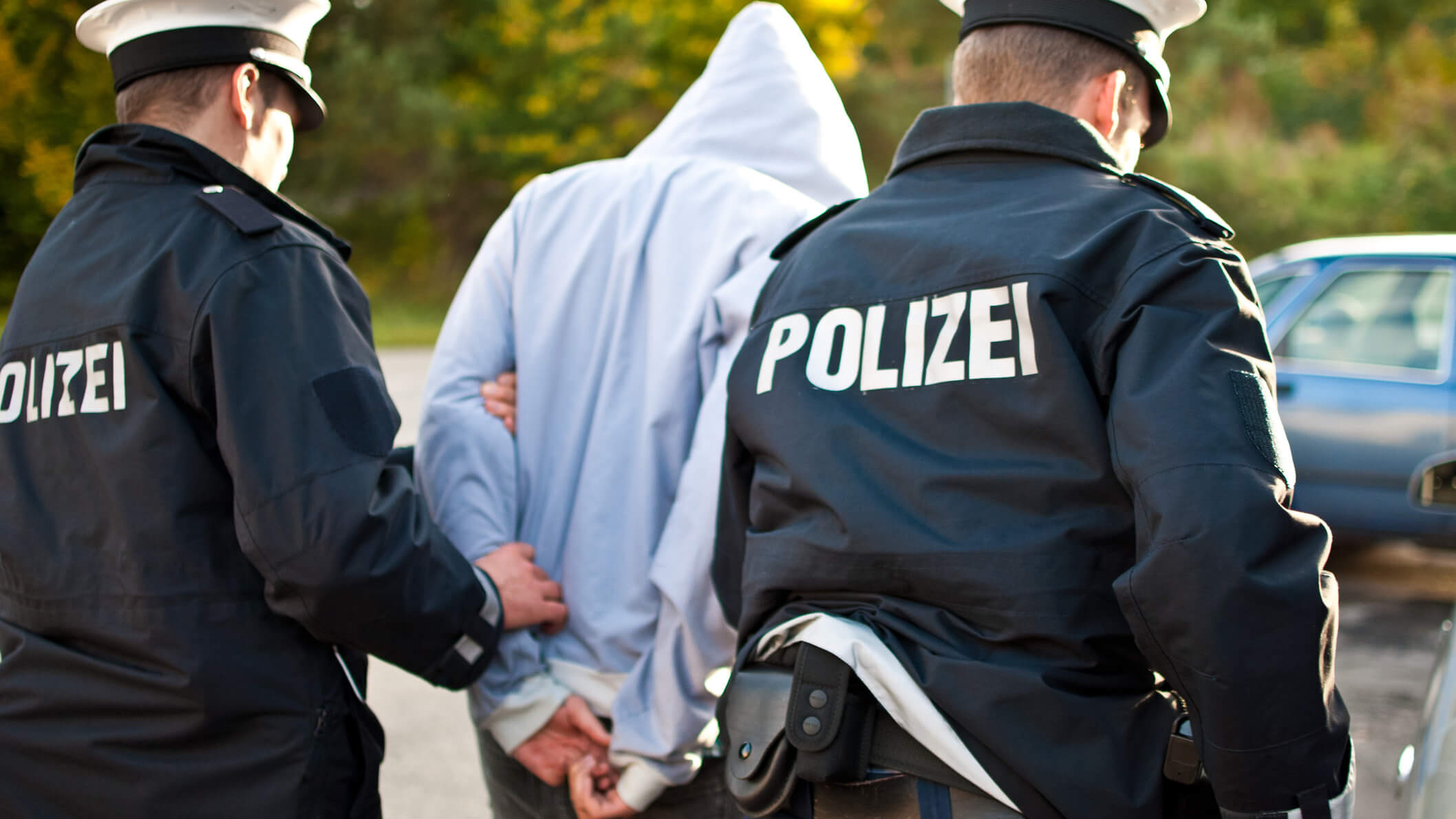 Ein Mann wird von zwei Polizisten abgeführt.