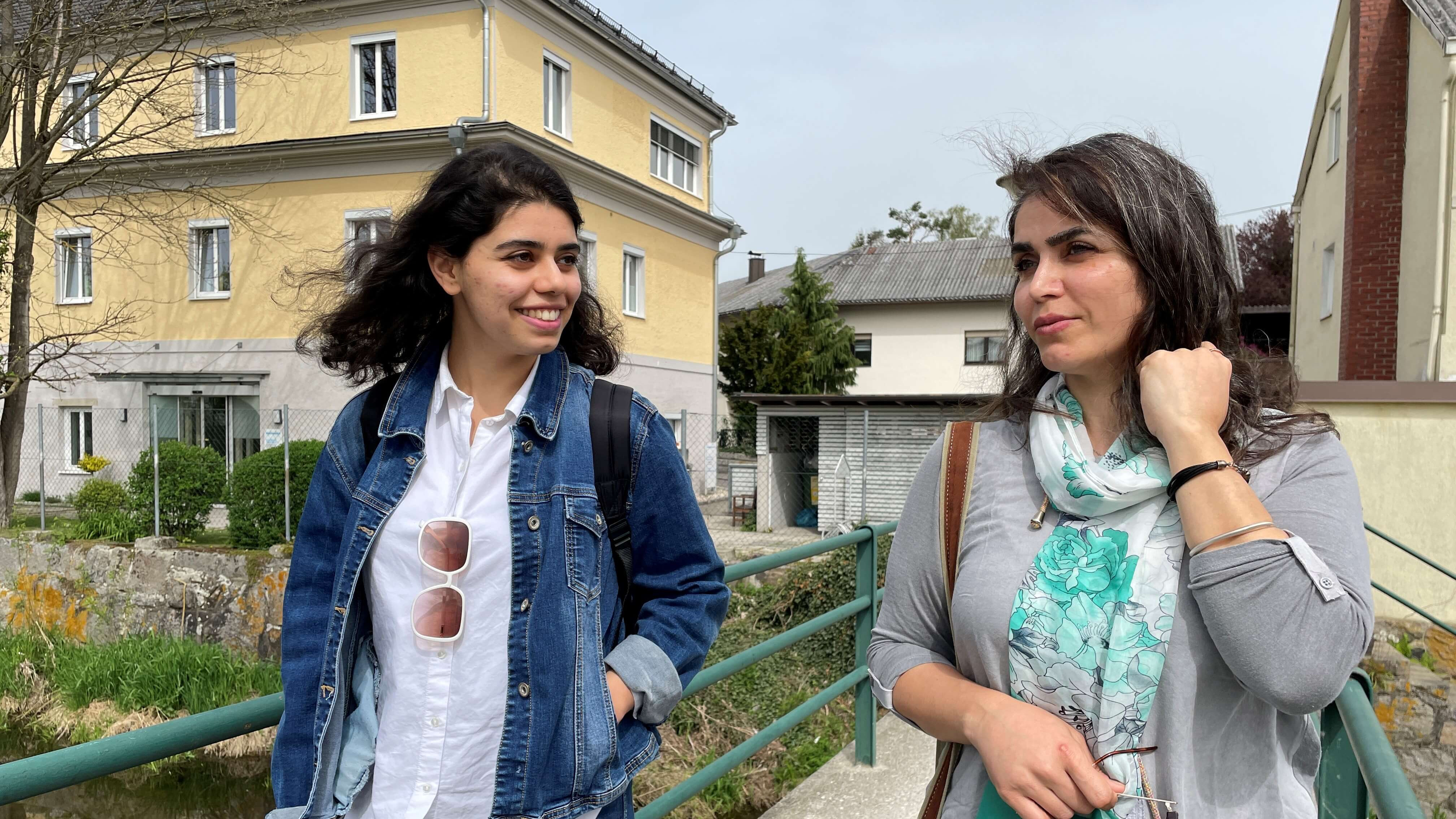 Zwei Frauen spazieren auf einer Brücke.