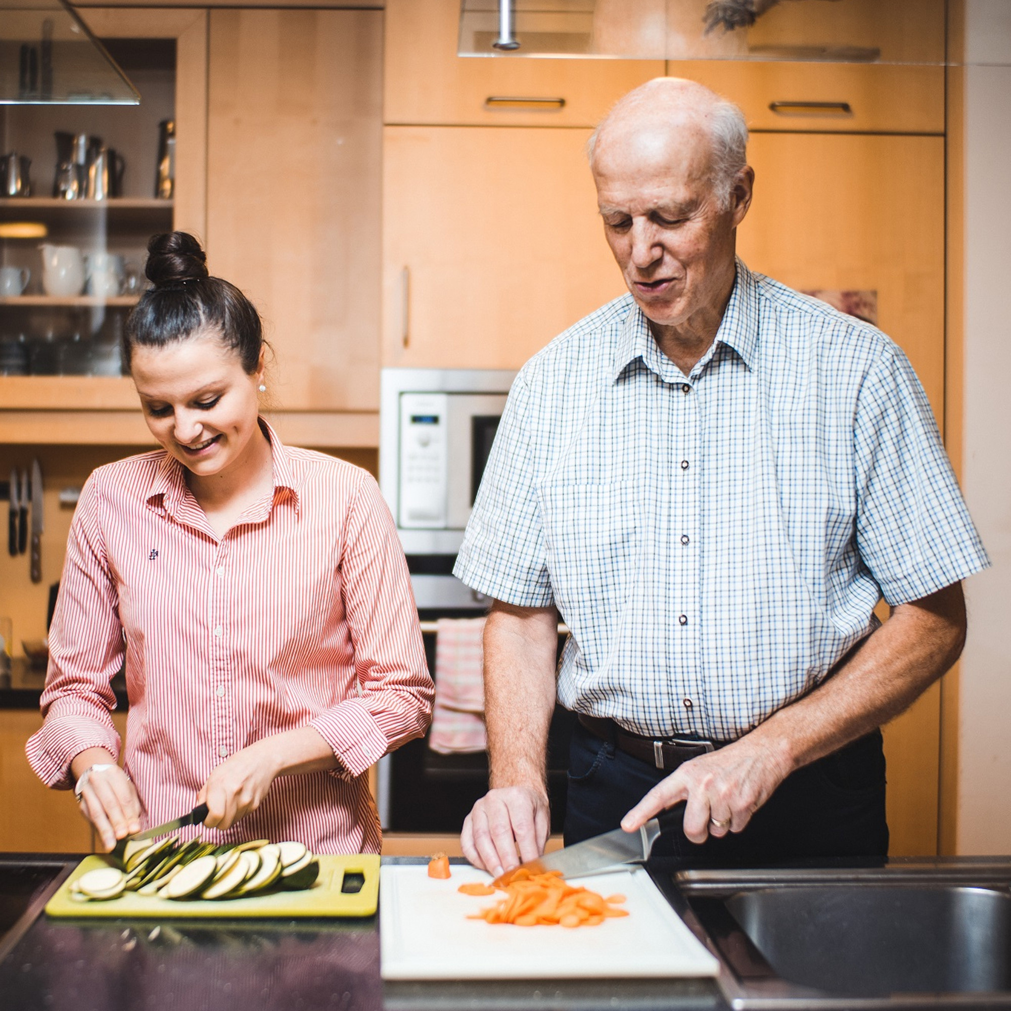 Eine junge Frau und ein älterer Mann kochen gemeinsam.