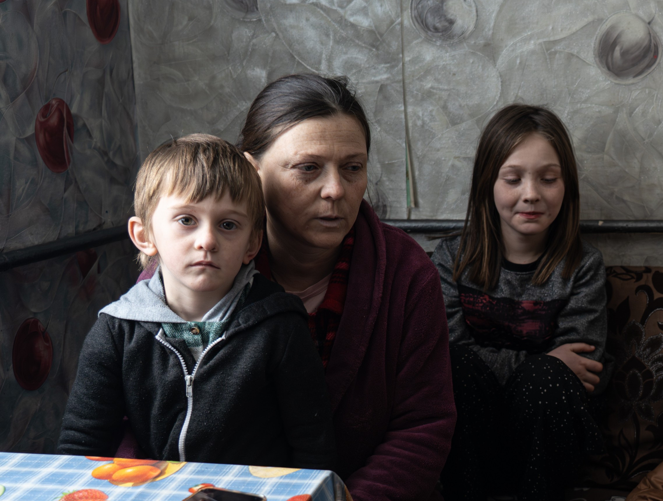 Eine Frau sitzt mit zwei Kindern auf einem Sofa.