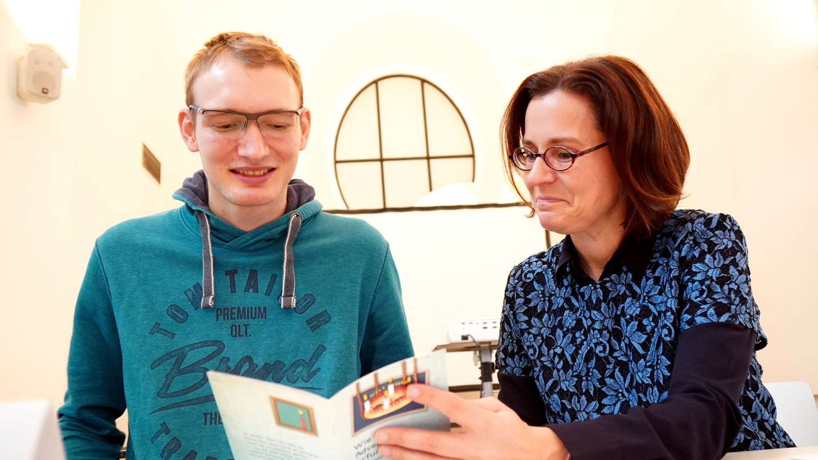 Christian Öllinger und Maria Moser schauen das Adventkranzbuch an