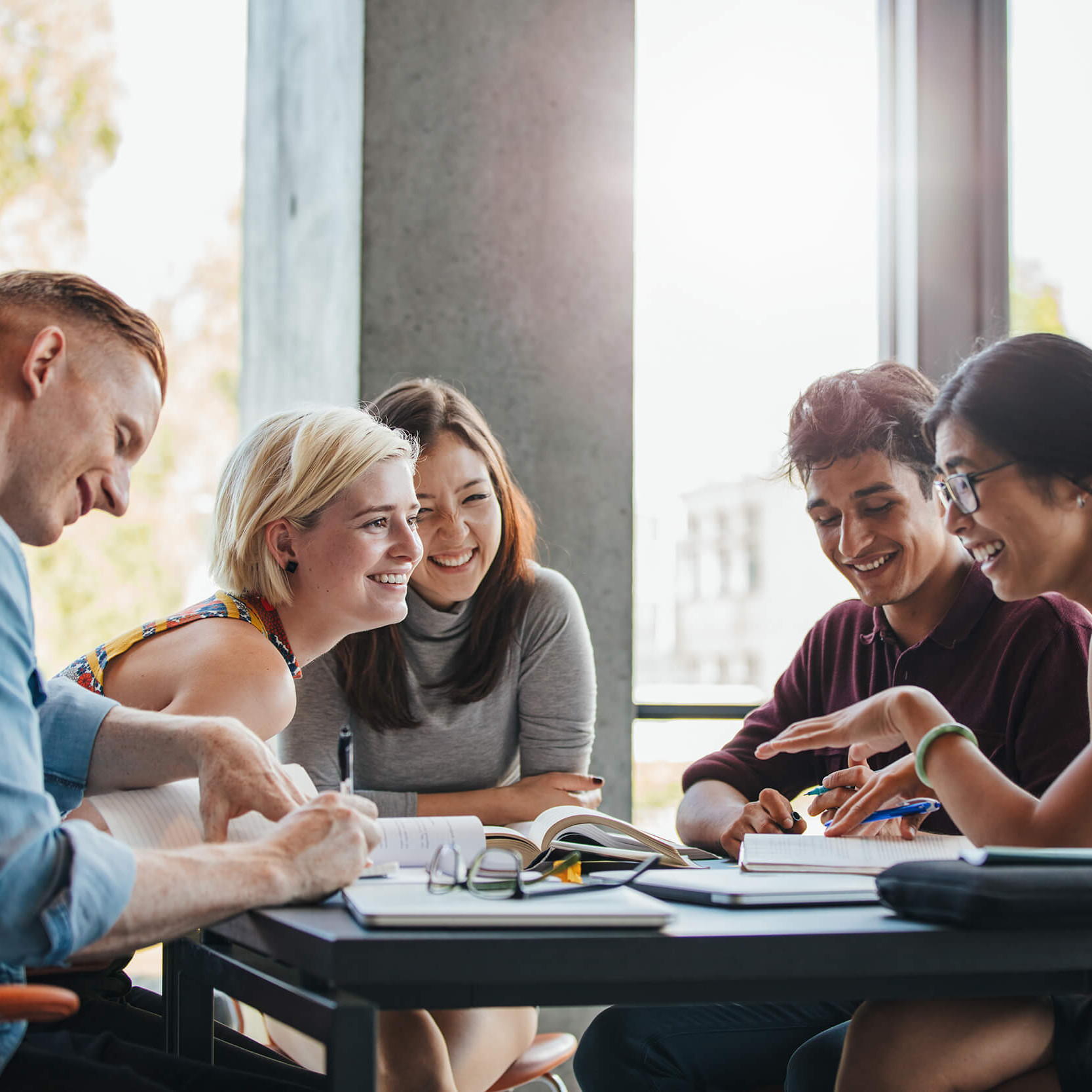 Mehrere junge Menschen sitzen an einem Tisch und lernen