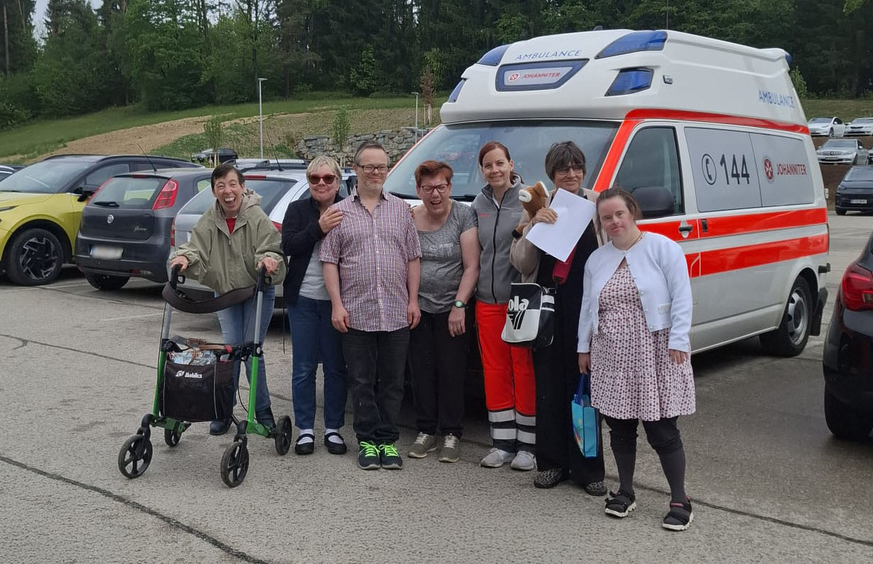 Teilnehmer:innen des Erste-Hilfe-Kurses der Leichter Lernen Akademie mit der Kursleiterin vor einem Rettungsauto