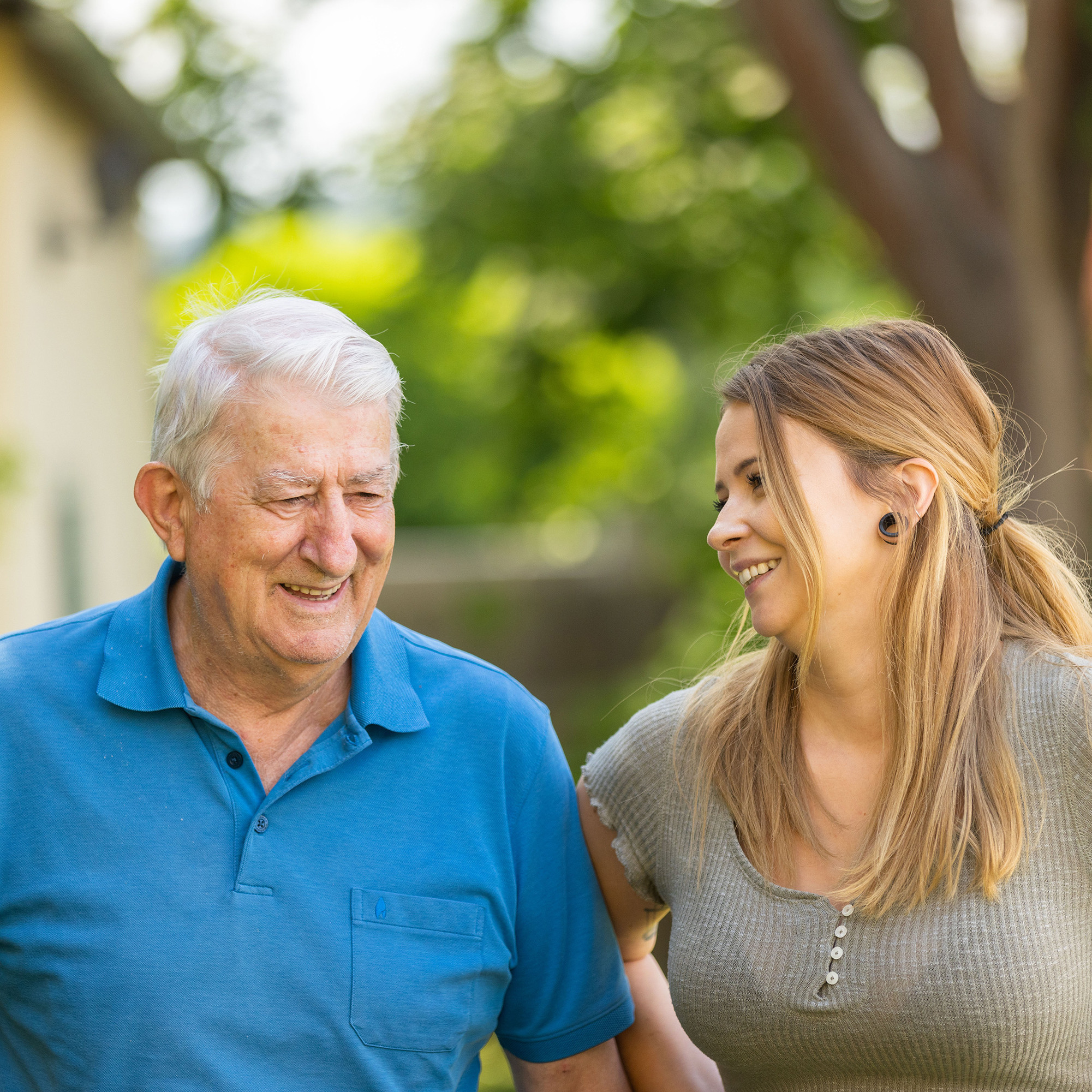 Ein älterer Herr und eine junge Frau draußen im Garten.